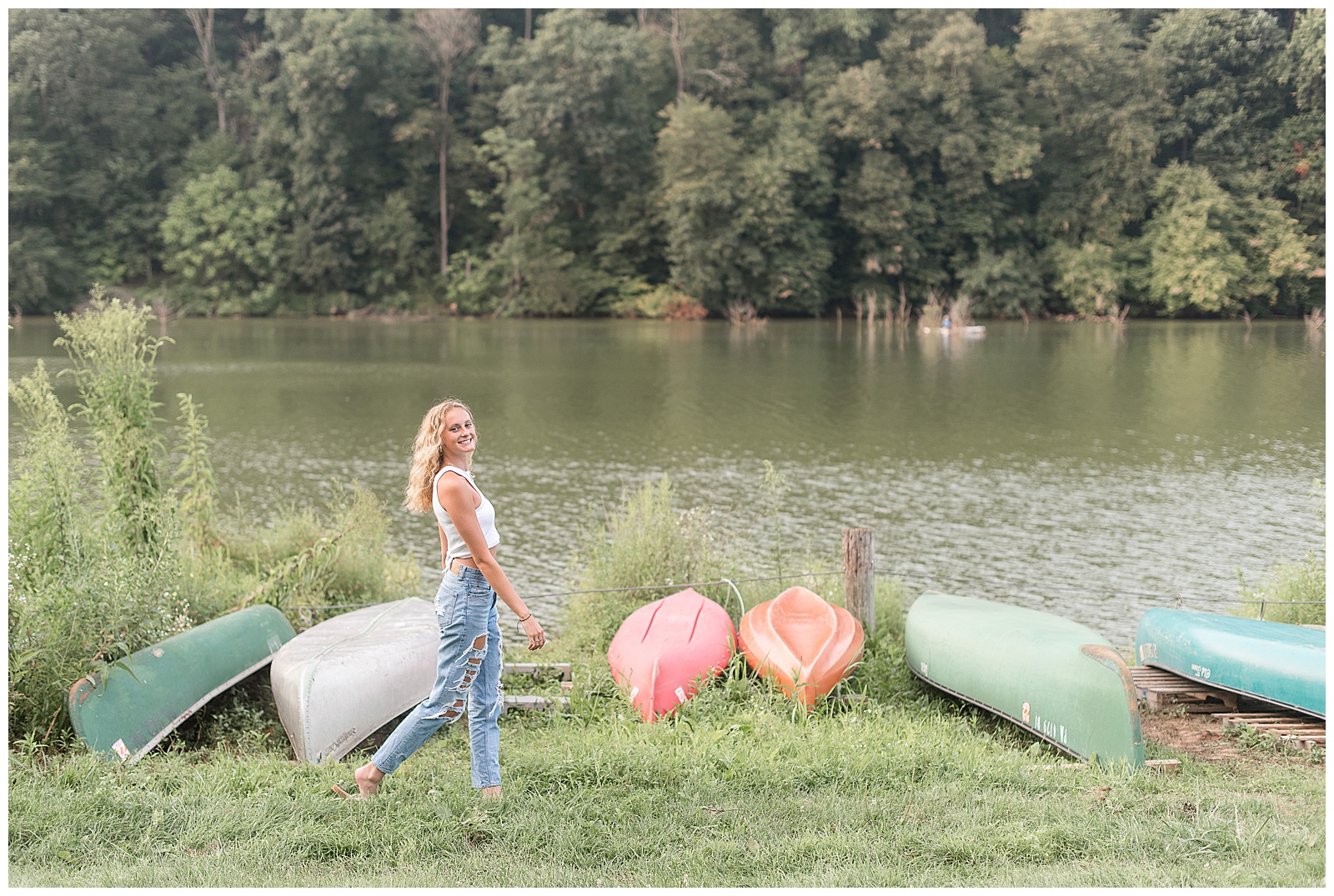 girl smiling at camera as she walks along row of colorful canoes at speedwell forge lake in lititz pennsylvania