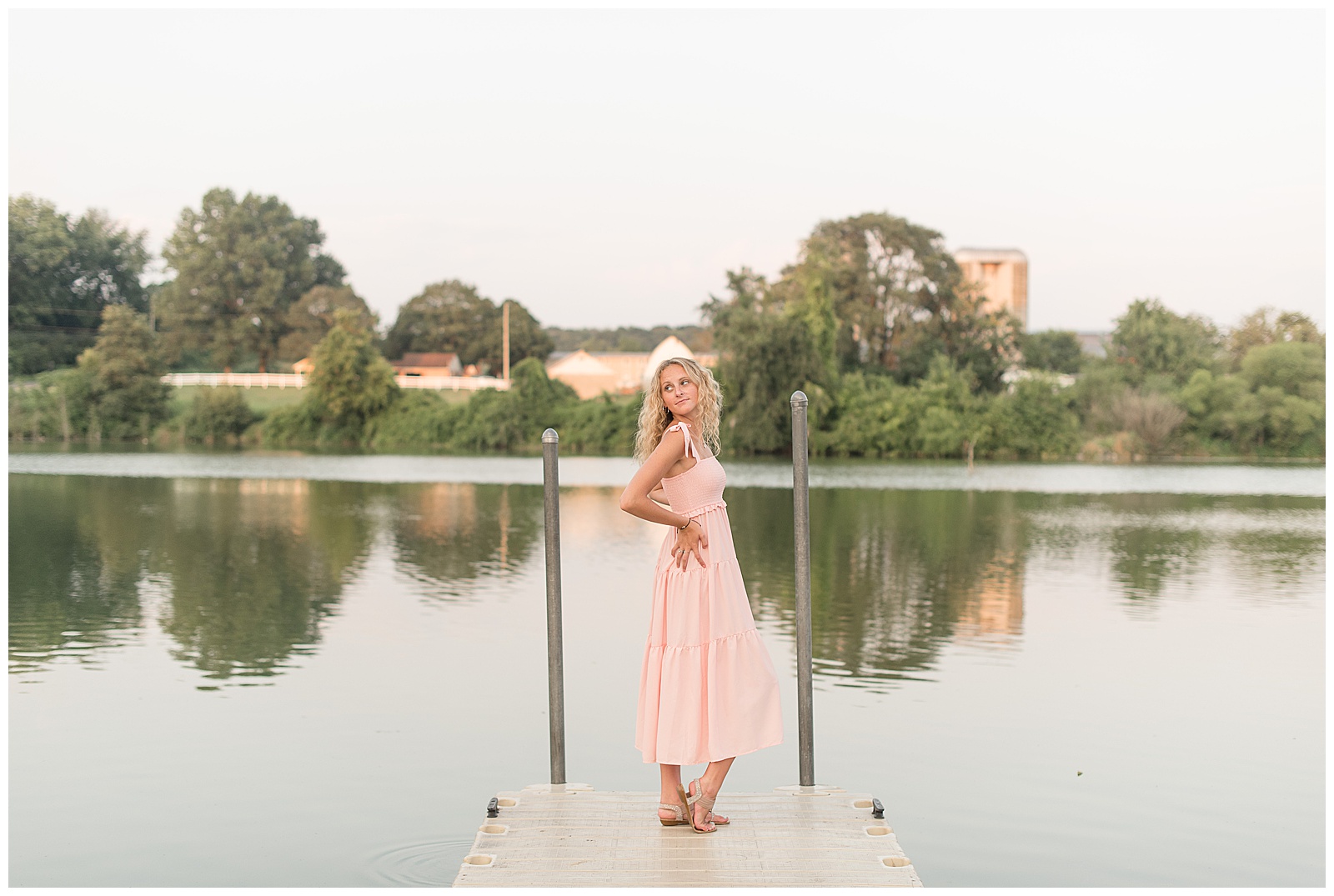 senior girl posing at end of dock at speedwell forge lake with hands on hips and right shoulder toward camera