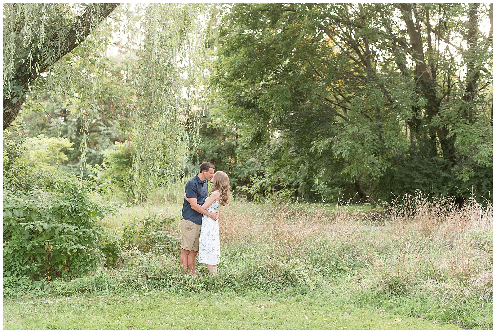 engaged couple hugging under willow tree on sunny evening at overlook park in lancaster pennsylvania