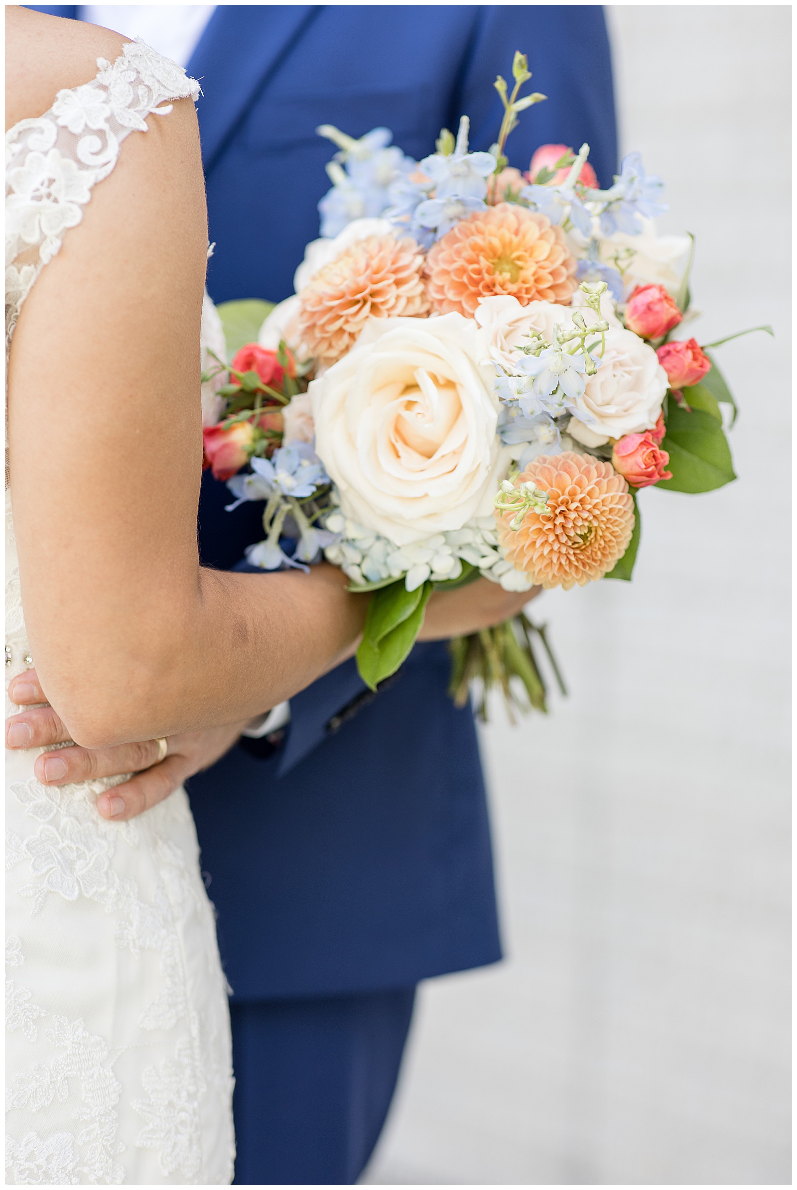close up photo of bride's bouquet as bride and groom hug with vibrant blue and orange colors in maryland