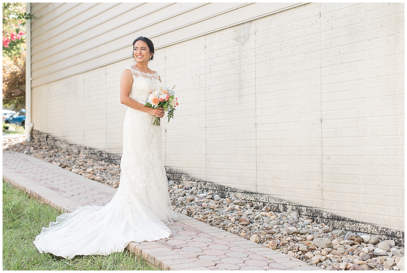 bride in white wedding gown standing along pathway holding vibrant bouquet looking over right shoulder in ellicott city maryland