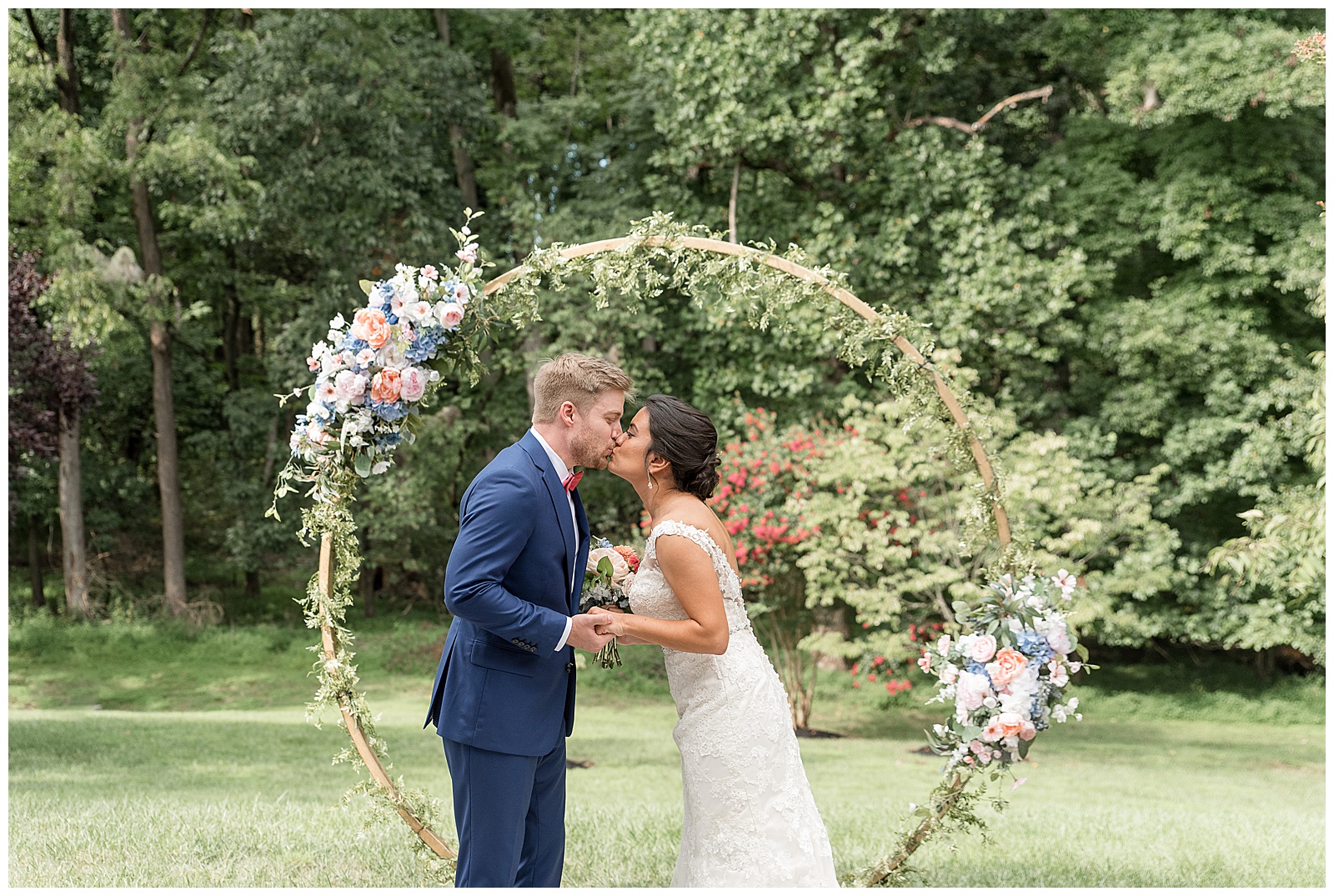 bride and groom share their first kiss by modern floral archway in ellicott city maryland at outdoor venue