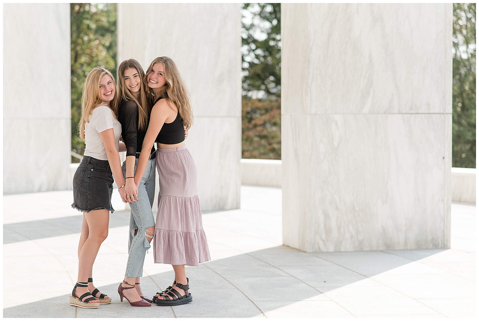 three senior girls hugging tightly as they lean forward with hands touching at founders hall