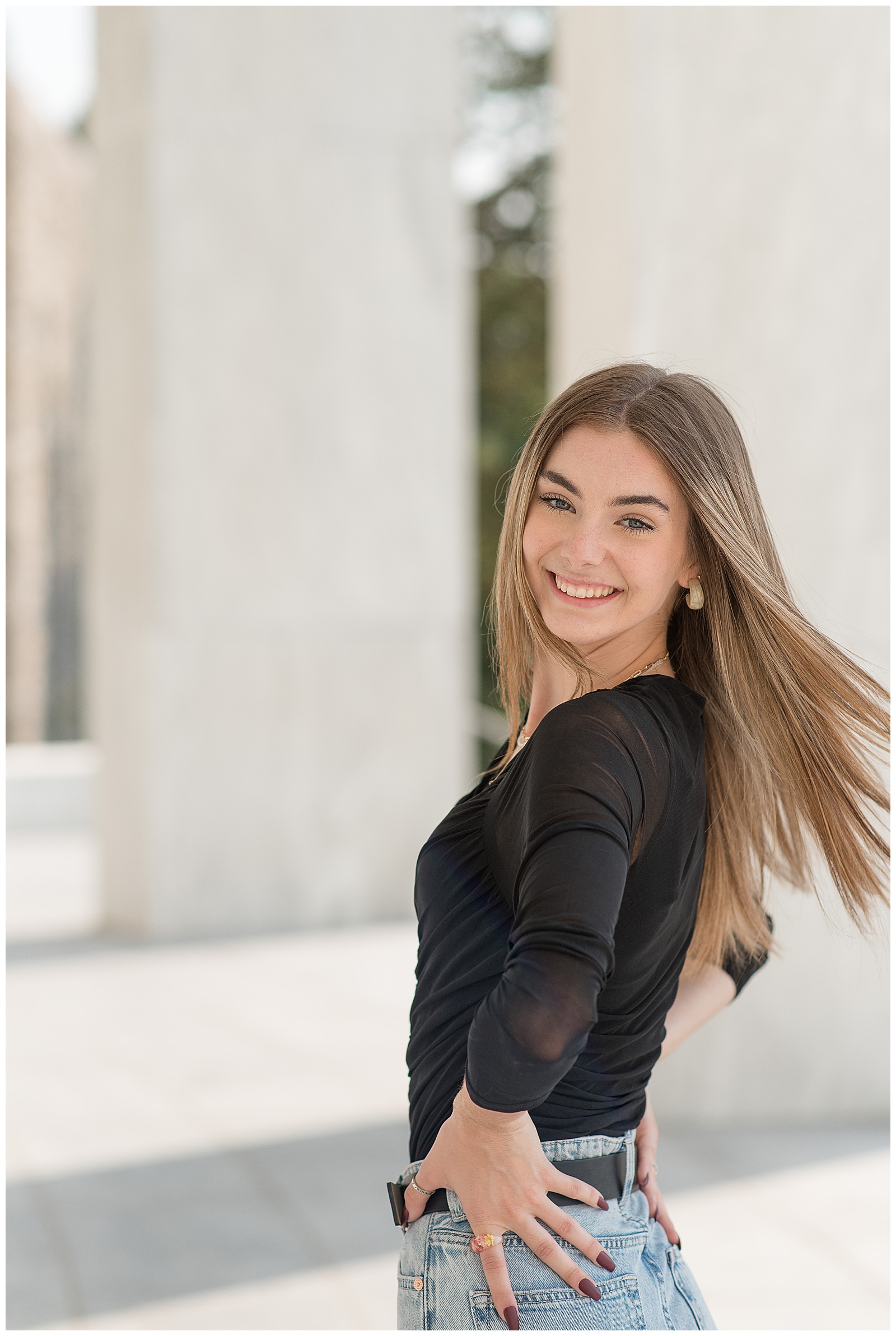 senior girl in black top spinning with her hair moving around her as she smiles at camera at founders hall in hershey pennsylvania