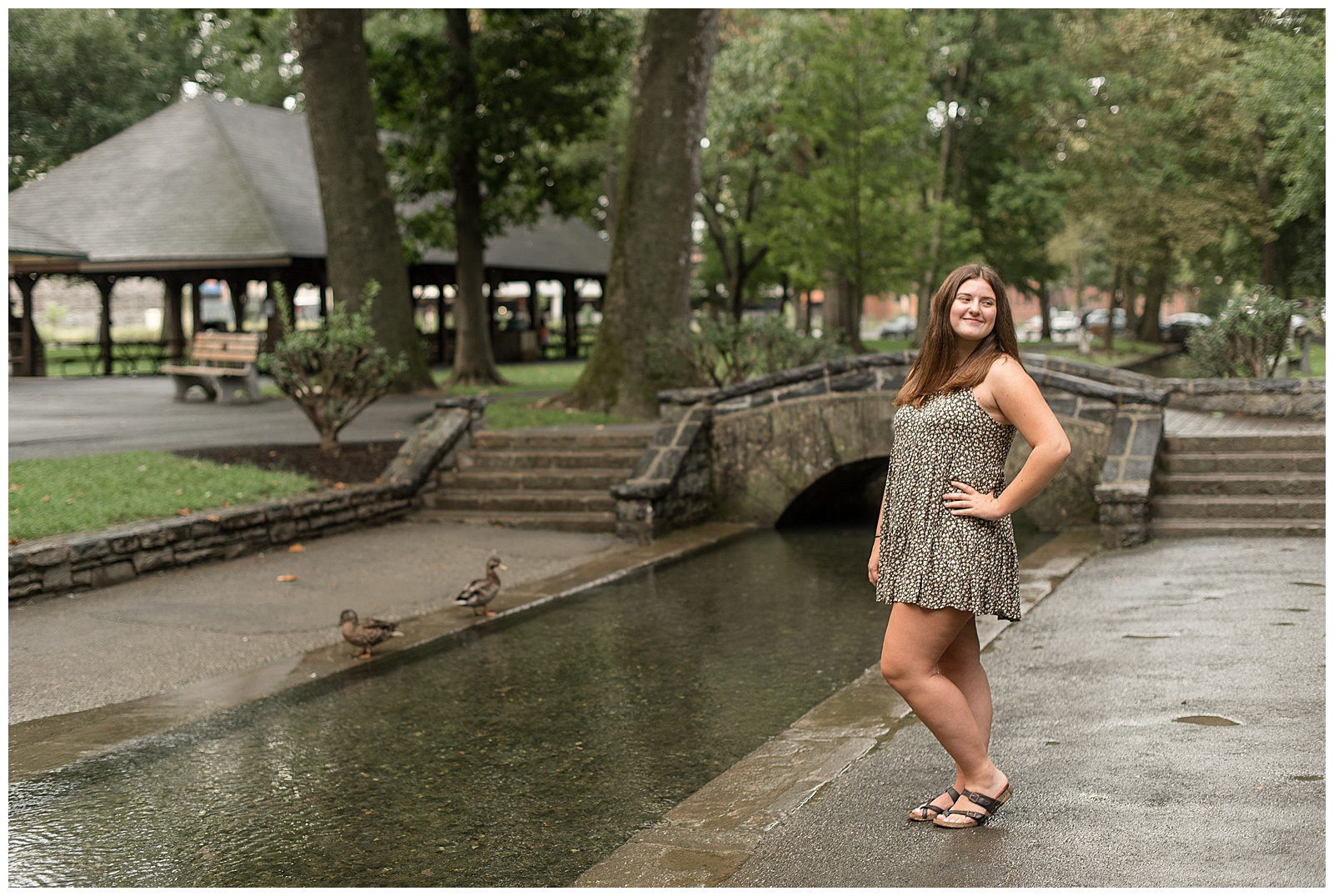 senior girl with left shoulder toward camera and hand on hip with left knee bent along stream at lititz springs park