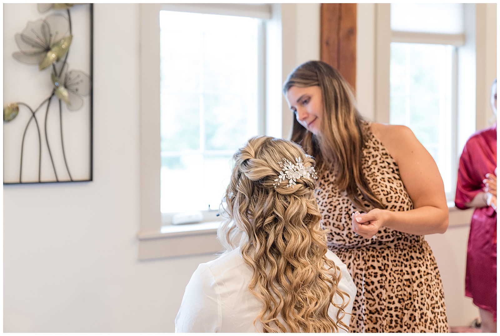 bride's back towards camera as she's seated and getting her makeup done by makeup artist inside bridal suite at the barn at silverstone