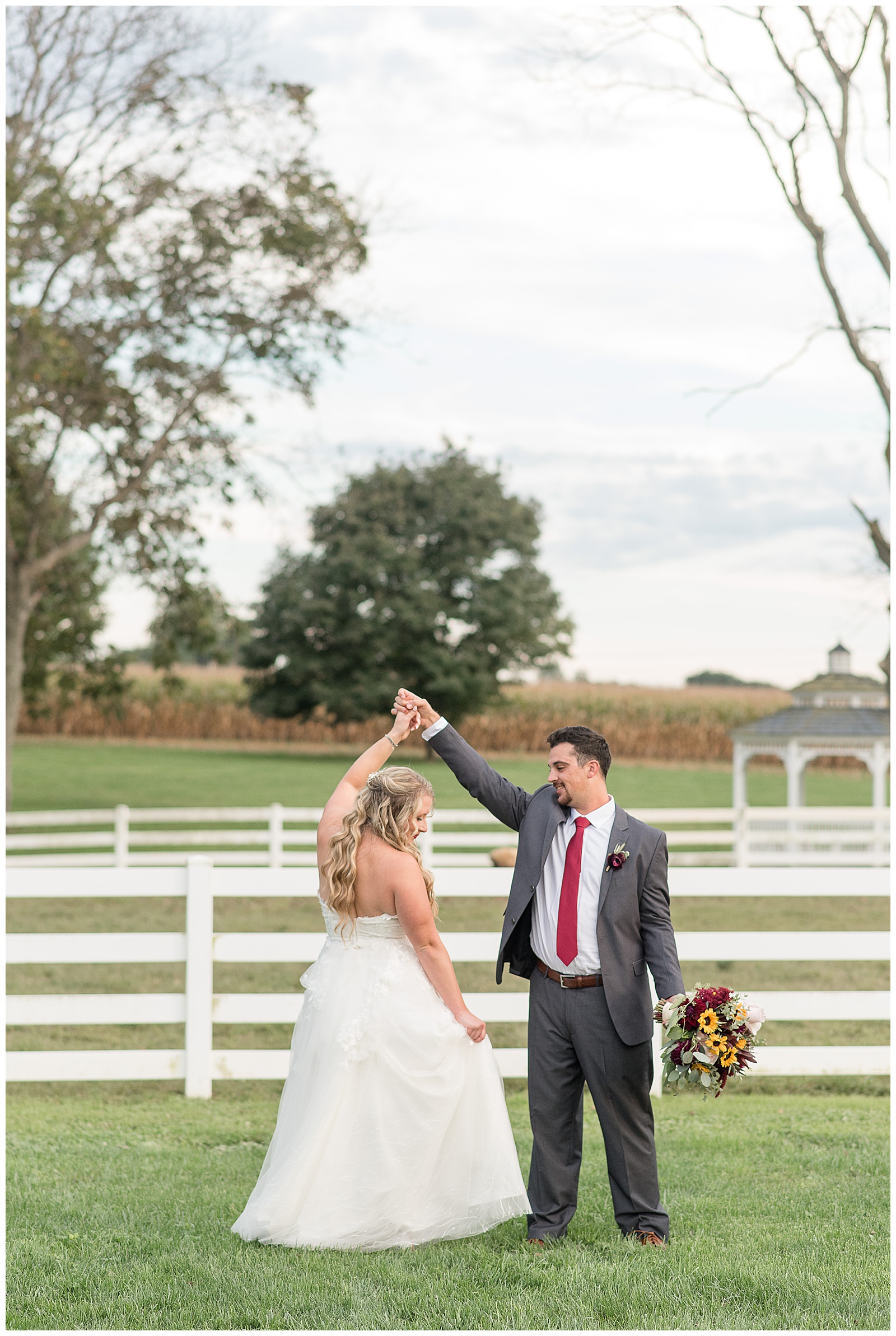 groom twirling bride under his right arm and she flares out her dress and he holds bouquet in left hand in lancaster pennsylvania