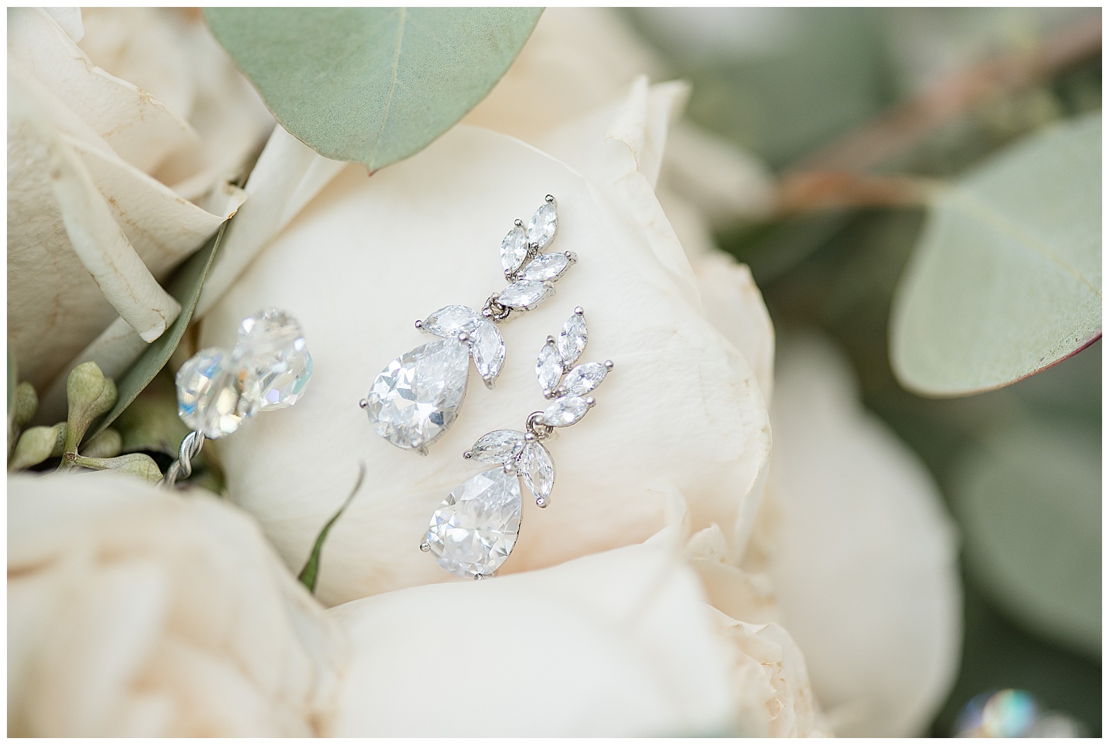 beautiful diamond earrings displayed atop white rose buds at cameron estate inn