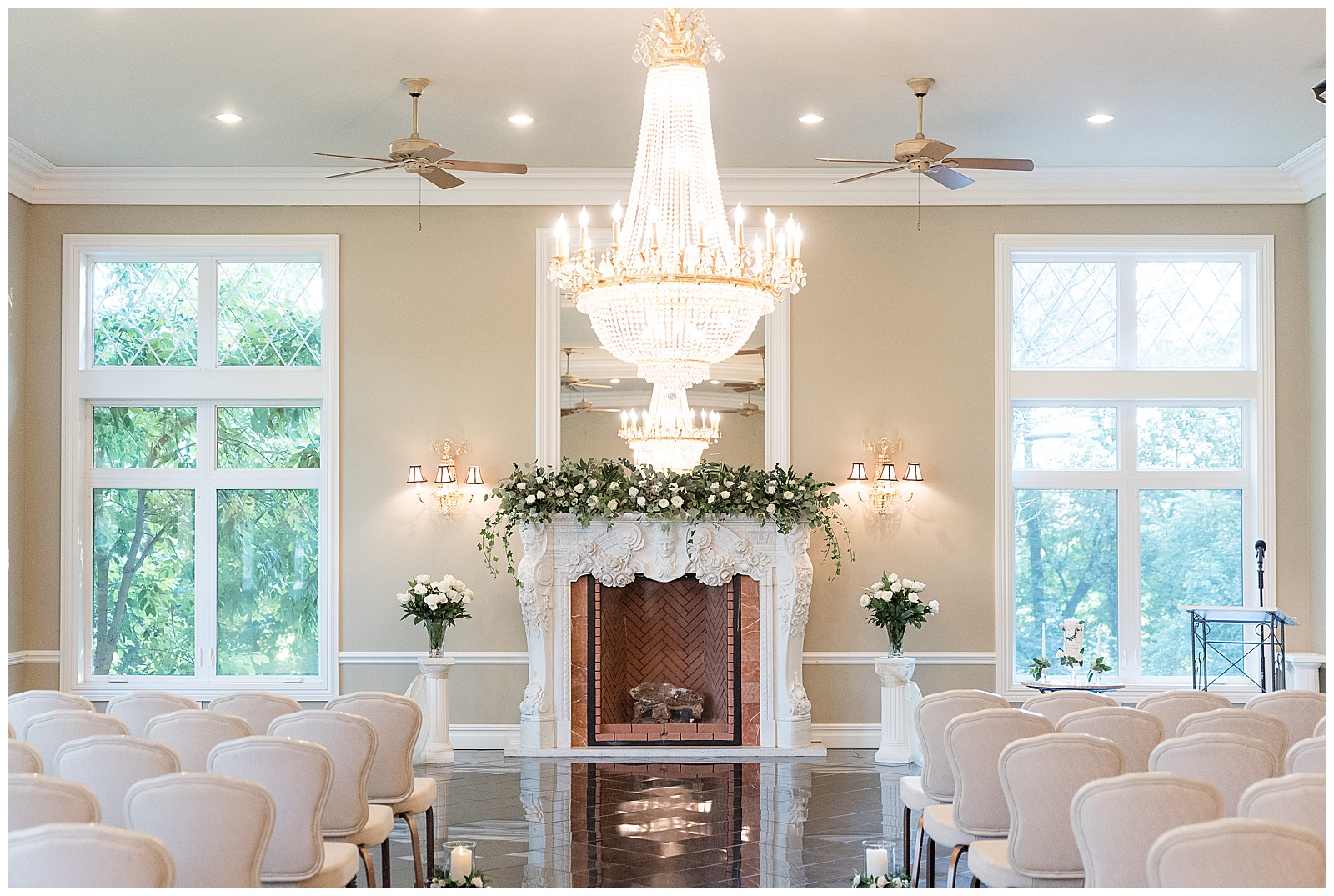 beautiful indoor wedding ceremony room with rows of white chairs and beautiful chandelier and fireplace at cameron estate inn