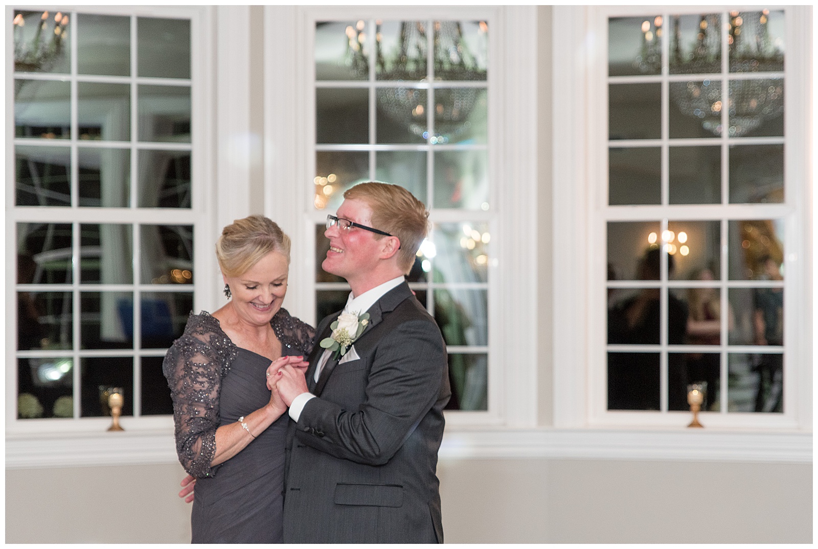 groom dancing with his mom during wedding reception by wall of white windows at cameron estate inn in mount joy pennsylvania