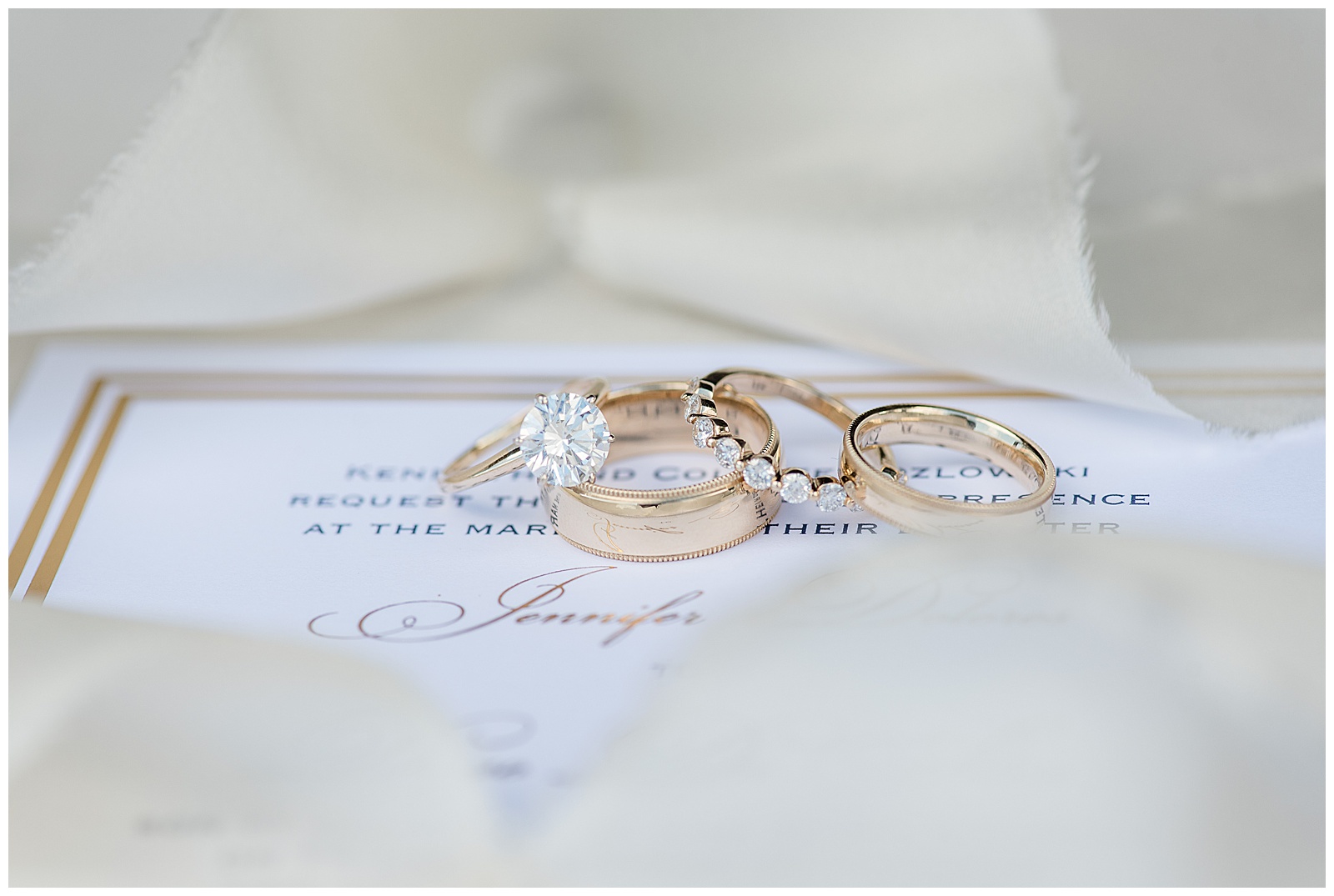 bride and groom's gold and diamond wedding rings displayed atop wedding invitation in northern new jersey 