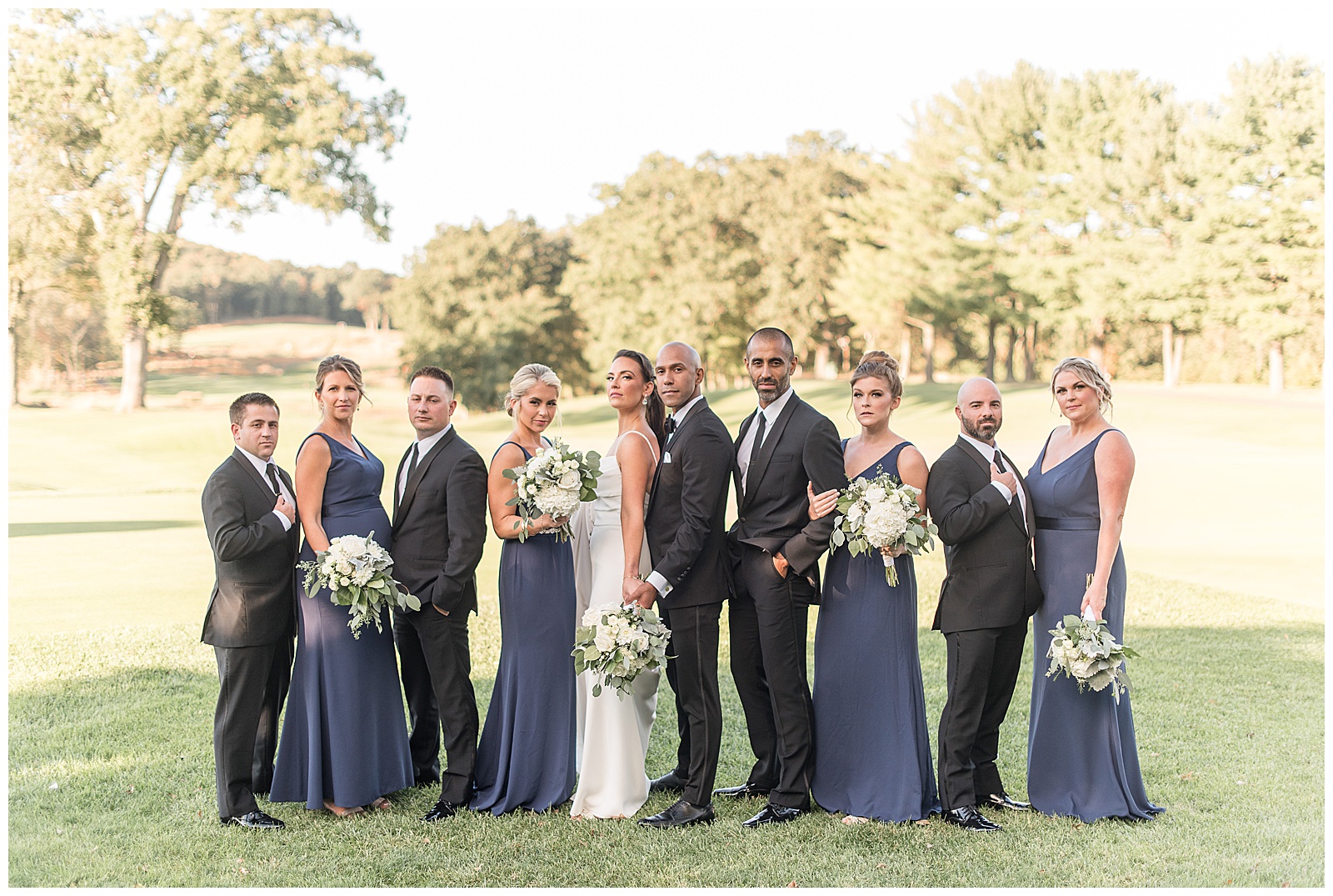 groom standing behind bride with bridal party surrounding them facing different directions on golf course at north jersey country club
