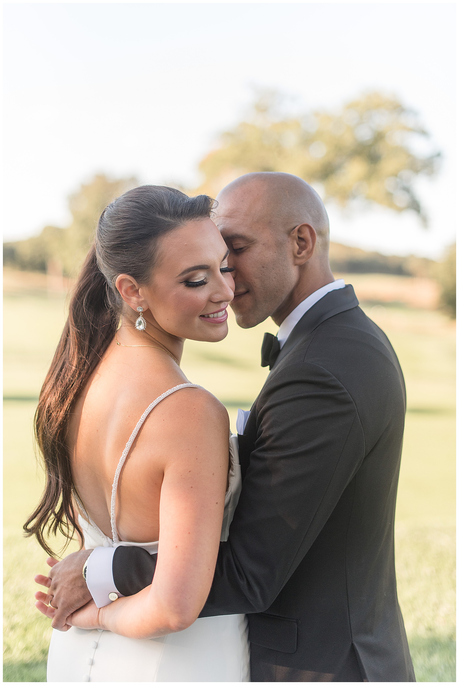 backs of bride and groom toward camera as she looks down and he kisses her left cheek at north jersey country club