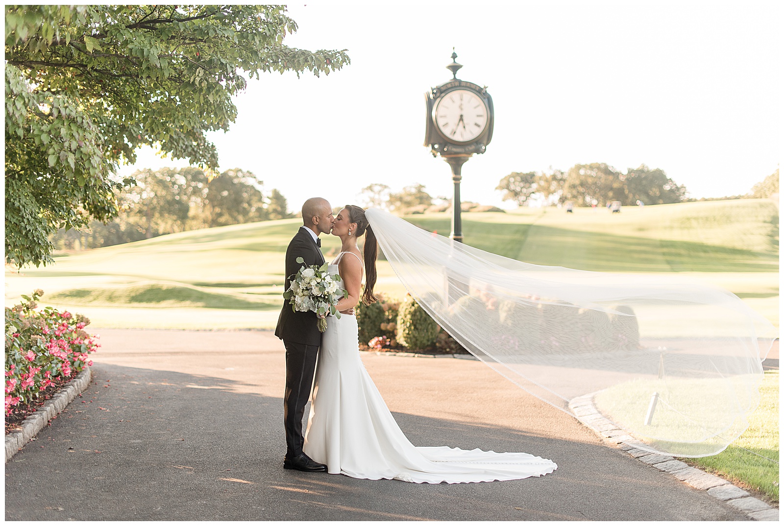 couple kissing with bridal veil blowing behind her and antique clock in background at north jersey country club