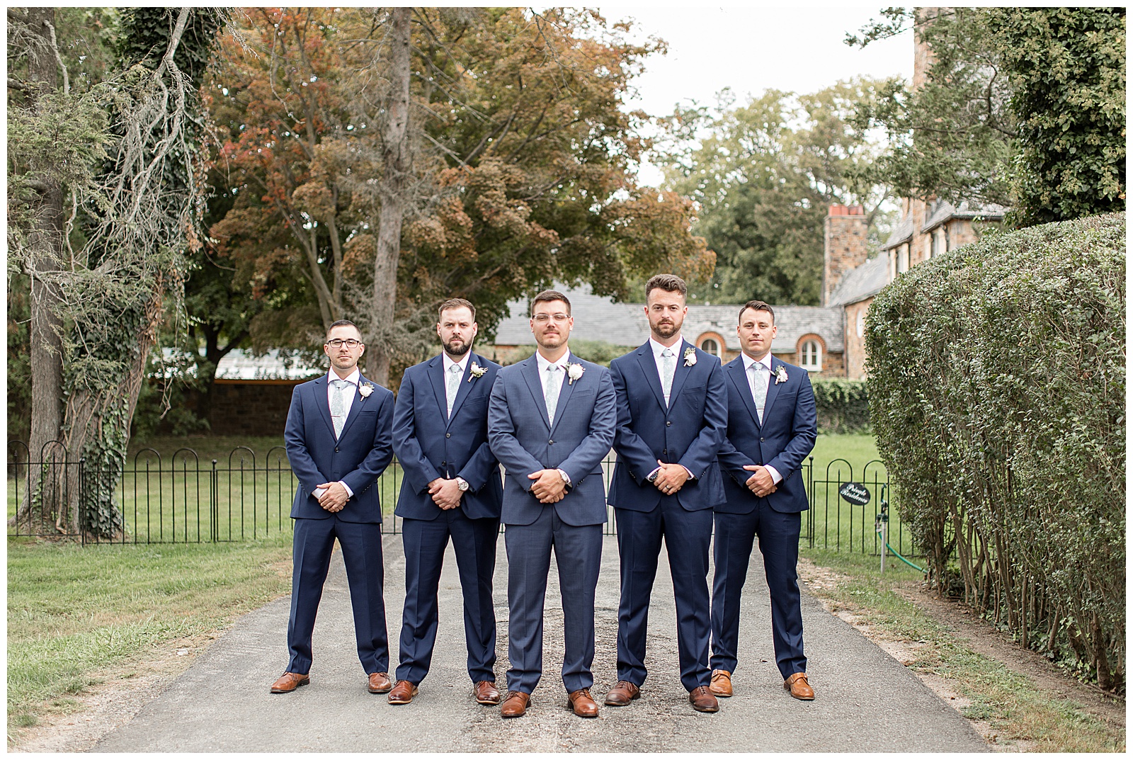 groom surrounded by four groomsmen on sidewalk with their hands folded in front of them at lauxmont farms
