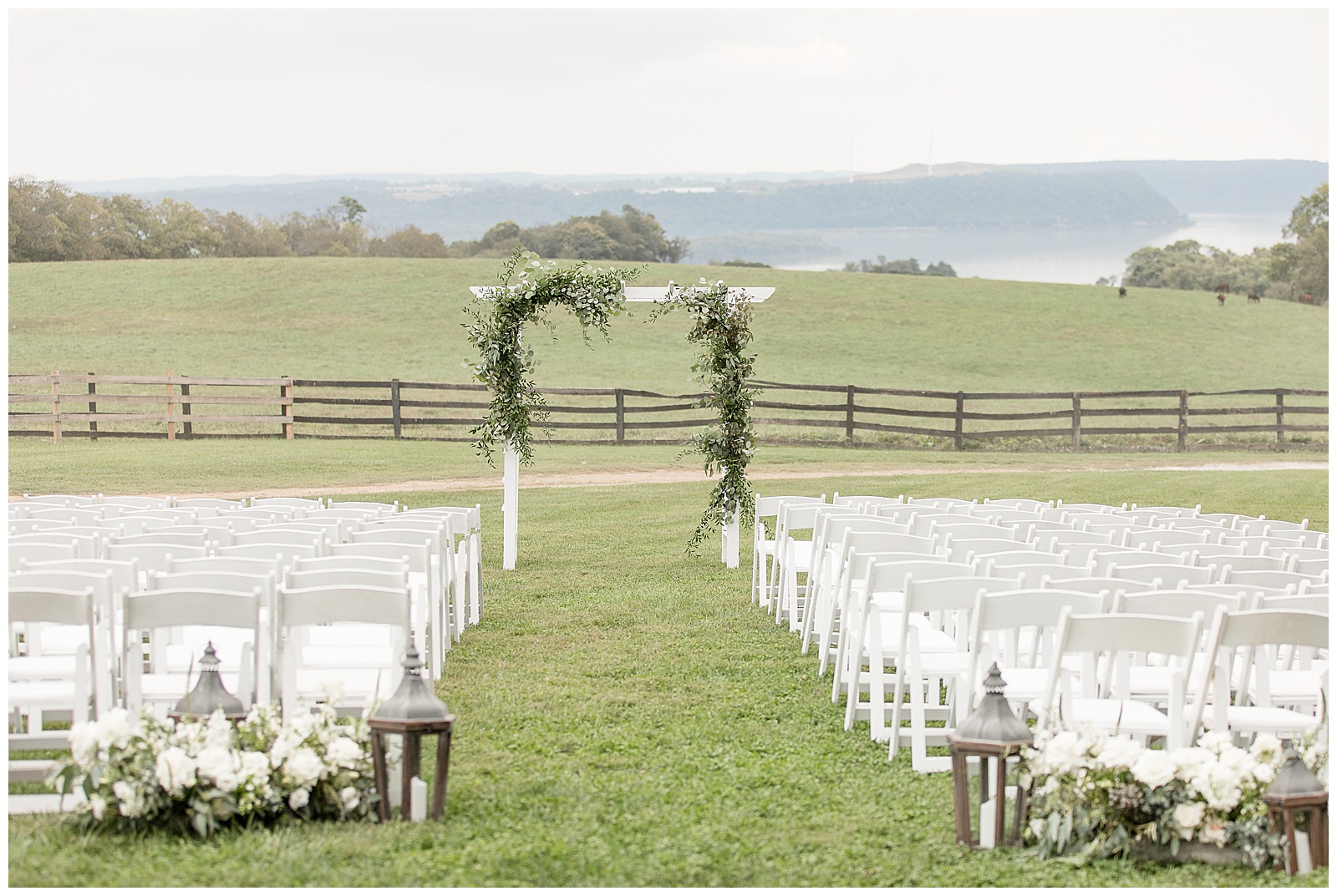 outdoor wedding ceremony with rows of white chairs and beautiful floral archway out in grass field at lauxmont farms