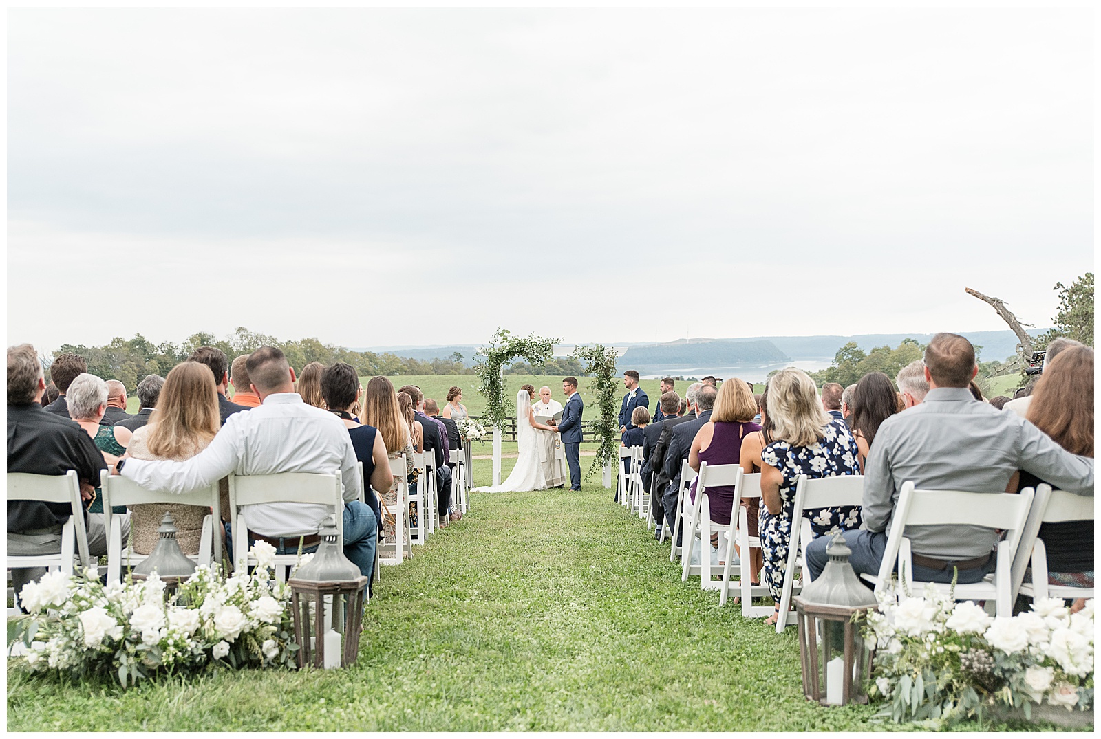 bride and groom holding hands during outdoor wedding ceremony with guests watching on cloudy day at lauxmont farms