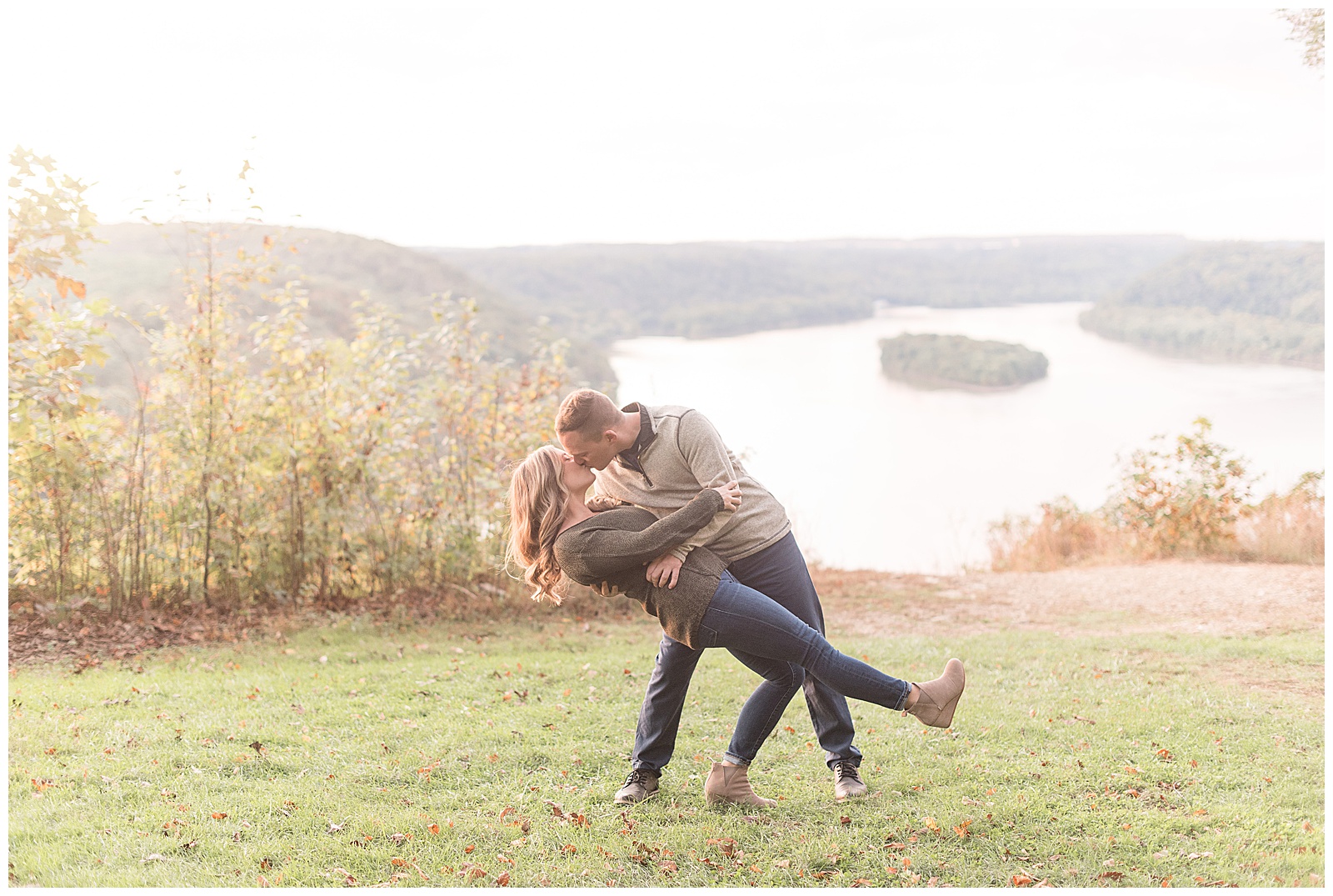 guy dipping girl back and kissing her in grass atop pinnacle overlook with susquehanna river behind them on fall day