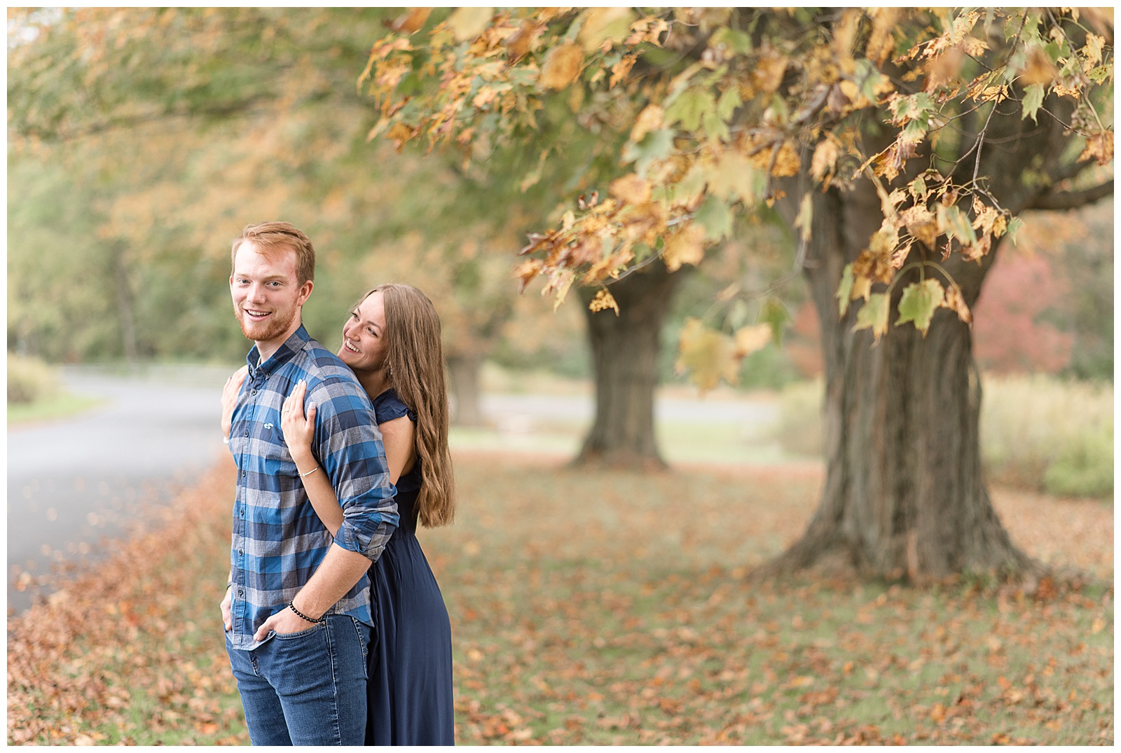 girl hugging guys from behind as they both smile with row of trees in background at middle creek wildlife