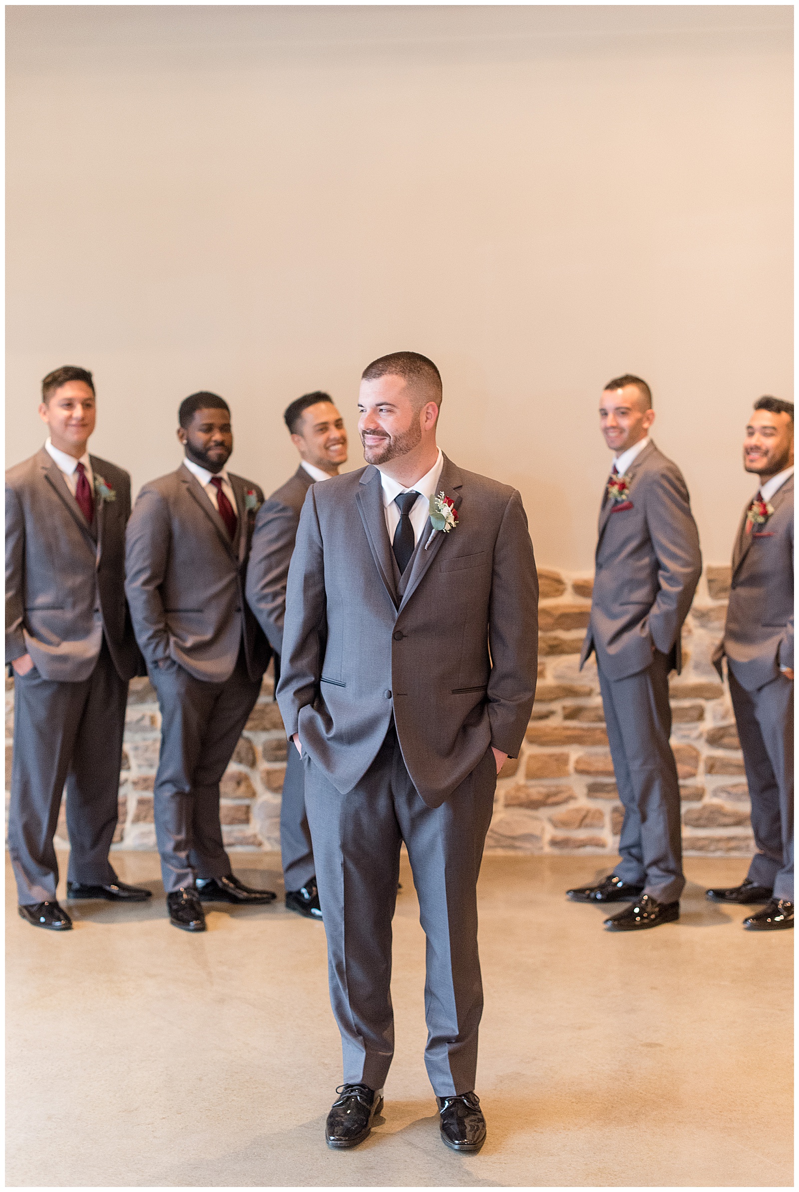 groom standing slightly in front of his groomsmen and looking over right shoulder smiling with hands in pockets at folino estate
