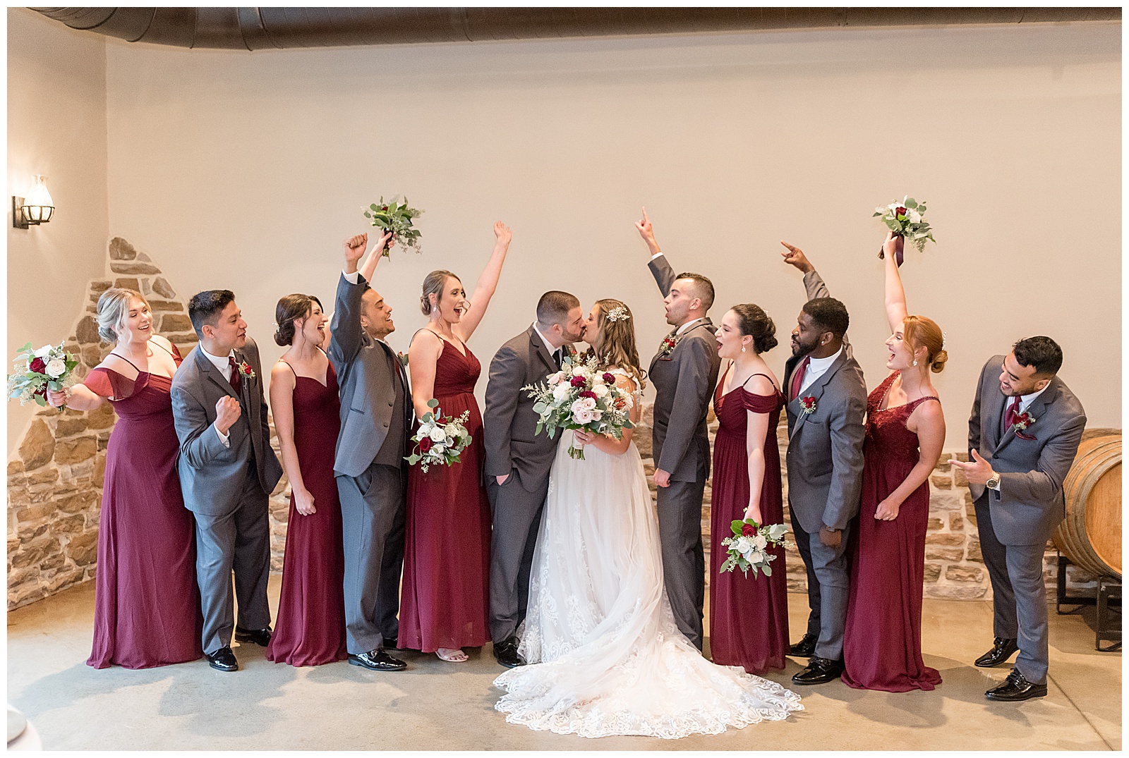bride and groom kissing with their bridal party raising their arms cheering inside folino estate