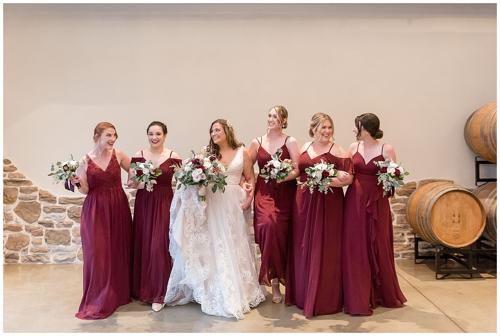 bride and bridesmaids with linked arms casually walking towards camera smiling inside folino estate in berks county pennsylvania