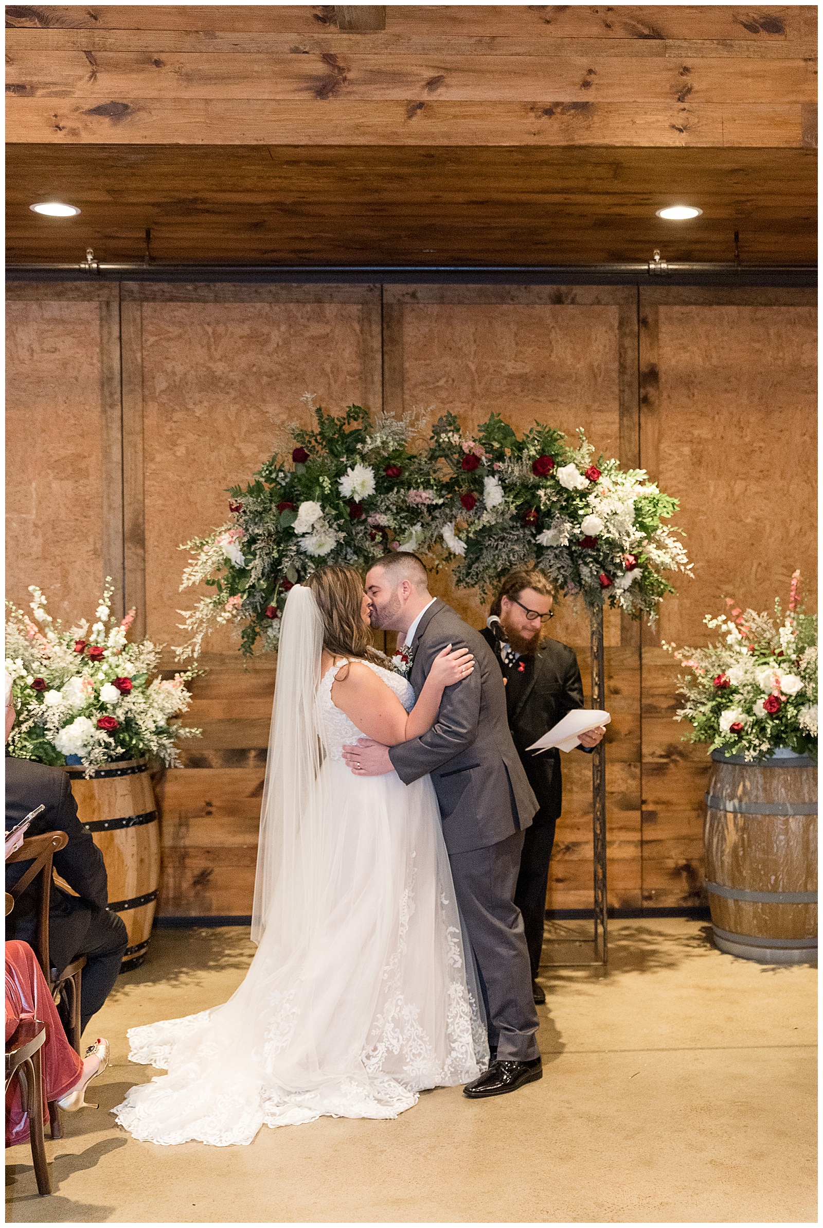 bride and groom sharing their first kiss as husband and wife by floral archway at folino estate in pennsylvania