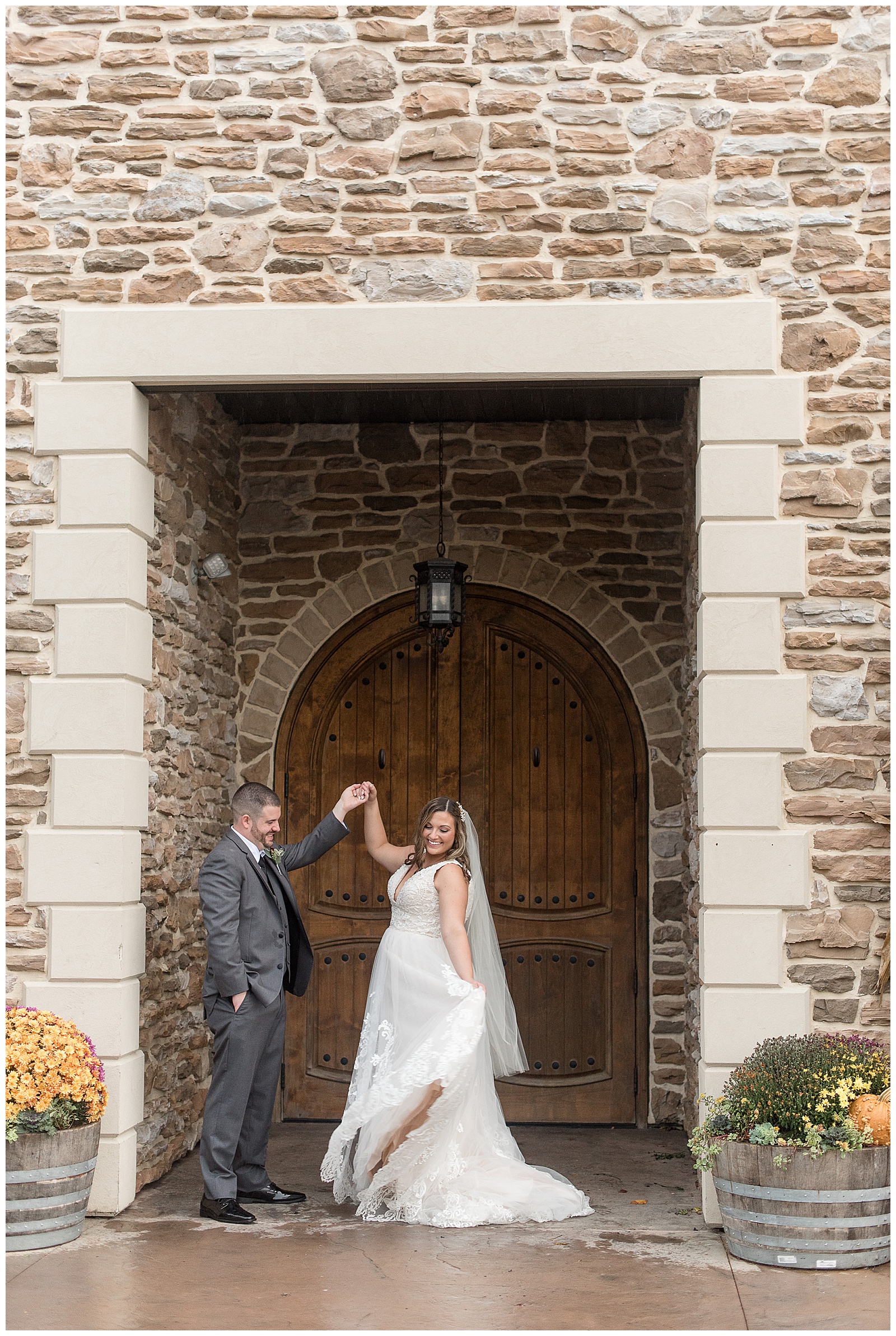 groom holding onto bride's right hand and lifting it high as she looks back and holds dress train with left hand by entrance to folino estate