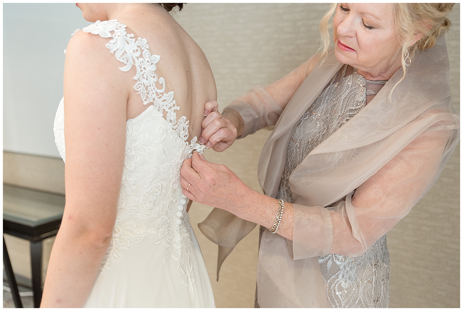 mother of the bride buttoning up the back of bride's white sleeveless wedding gown in collegeville pennsylvania