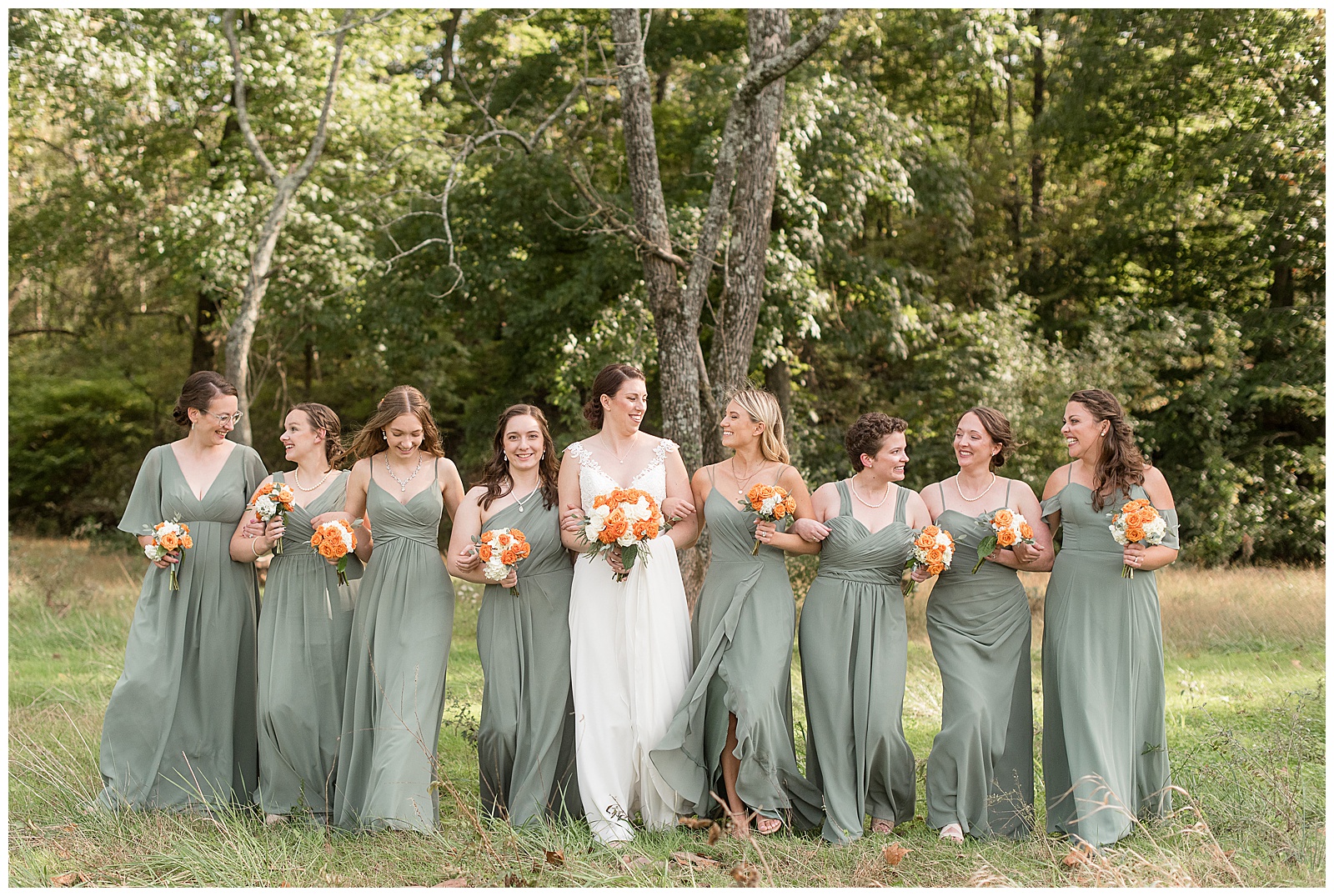 bride and bridesmaids all holding orange and white bouquets walking towards camera in collegeville pennsylvania