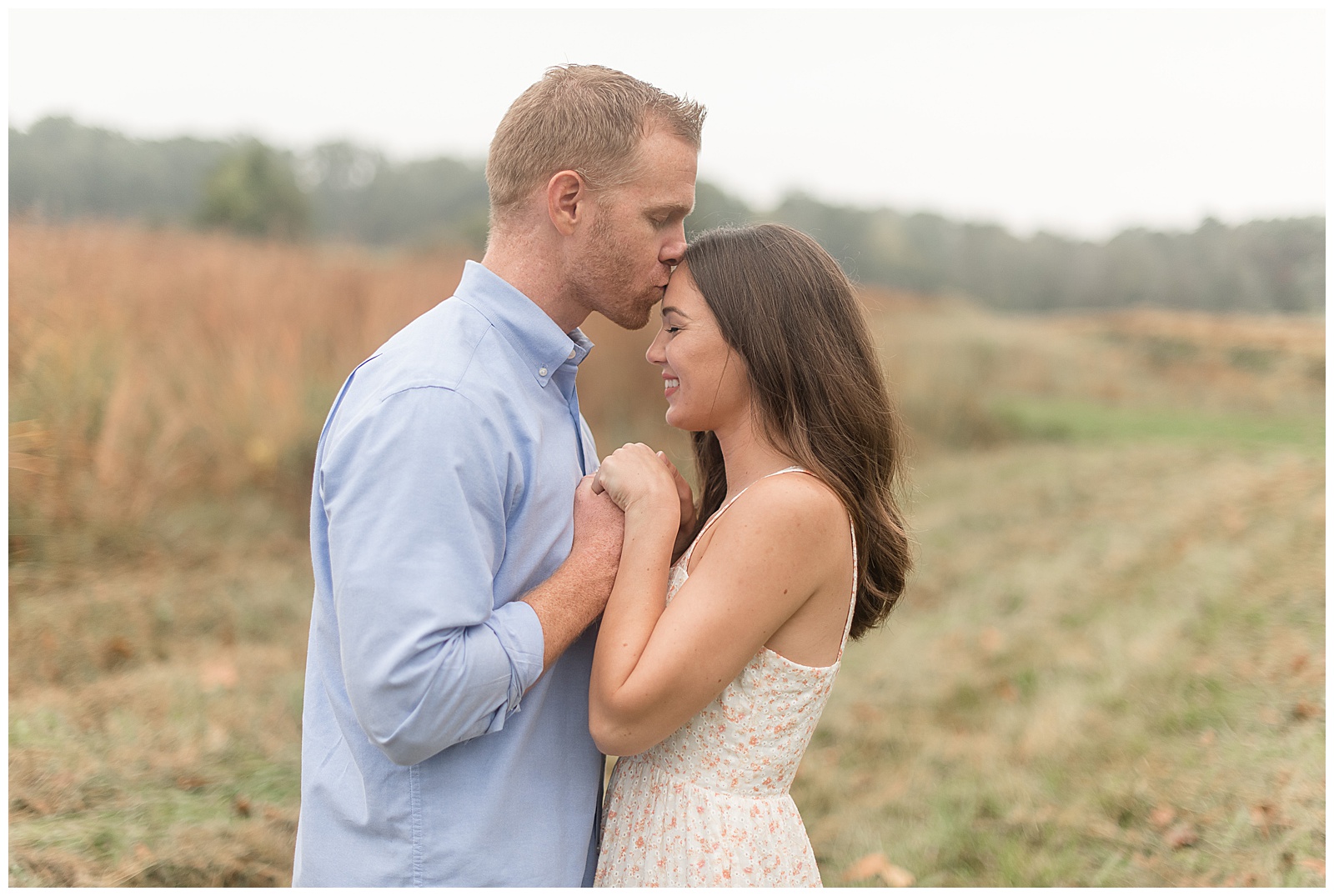 engaged couple hugging tightly as guy kisses top of girl's head with field behind them in chester county pennsylvania