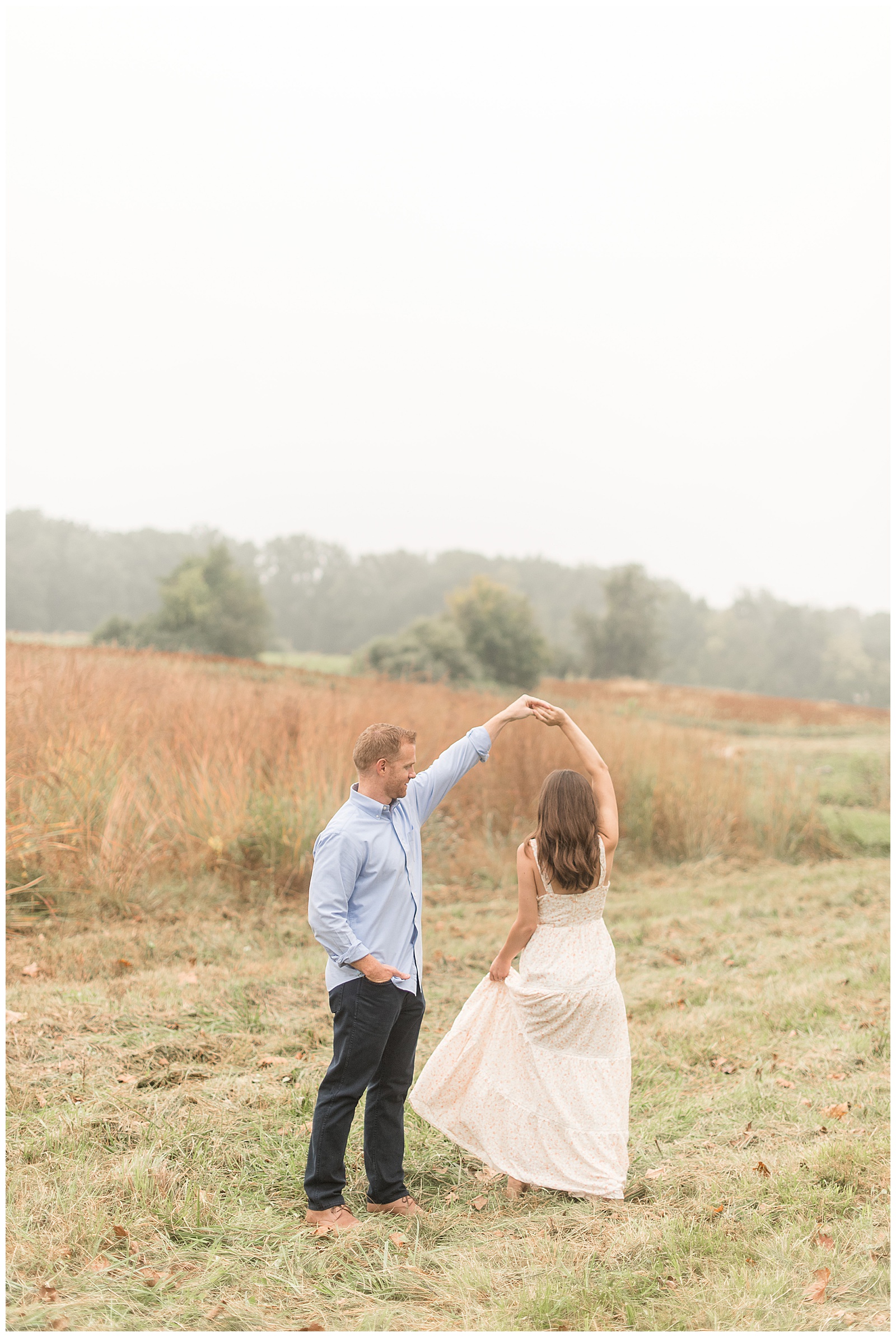 guy twirling girl under left arm in hay field with tall grasses behind them in chester county pennsylvania