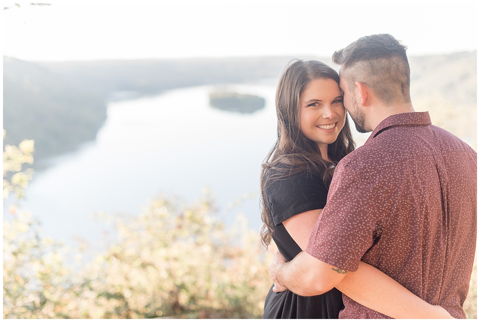 engaged couple hugging on right side of photo with guy's back toward camera and girl looking at camera smiling at pinnacle overlook