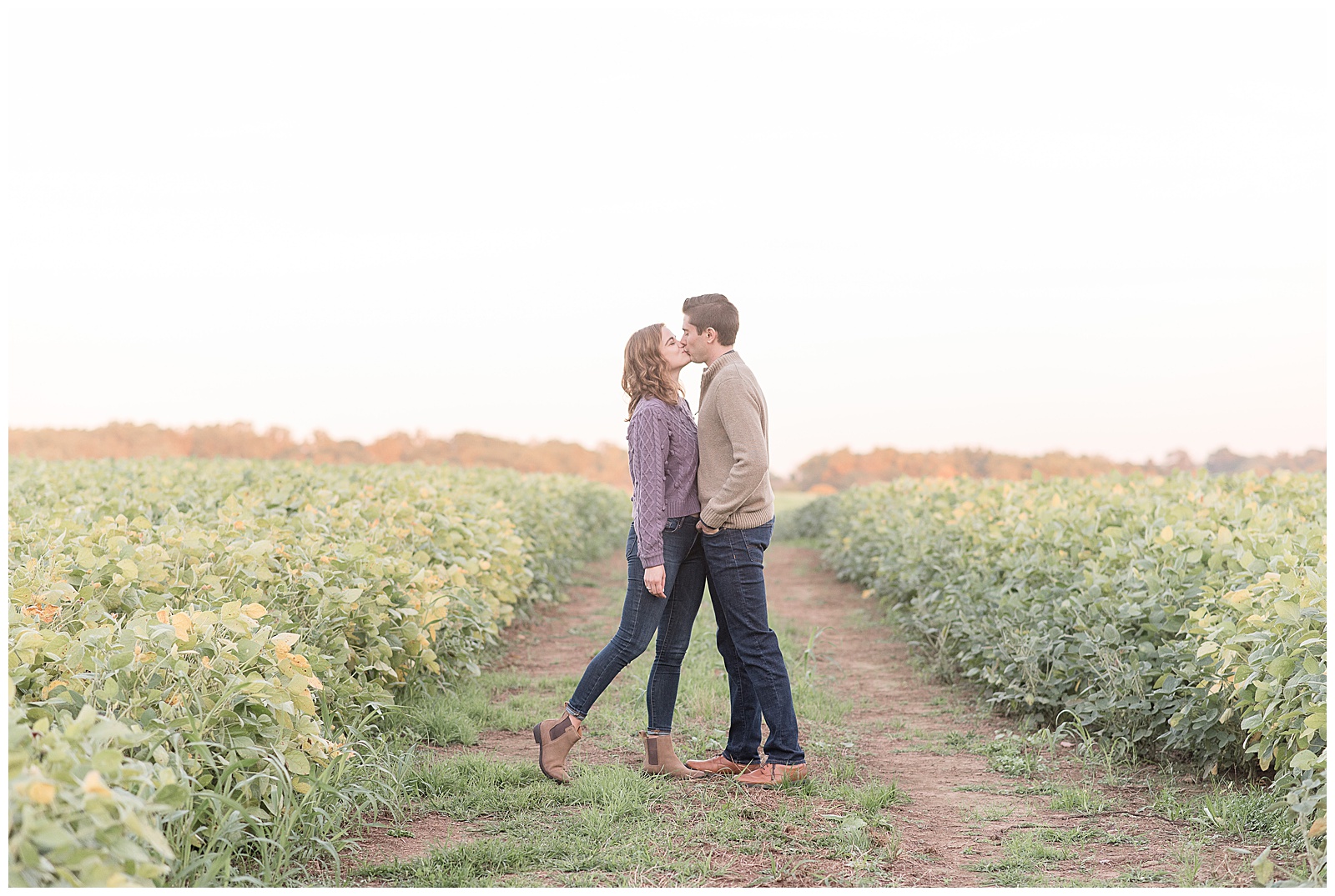 engaged couple facing each other kissing while standing on dirt path between two fields of plants at elizabeth furnace in lititz pennsylvania