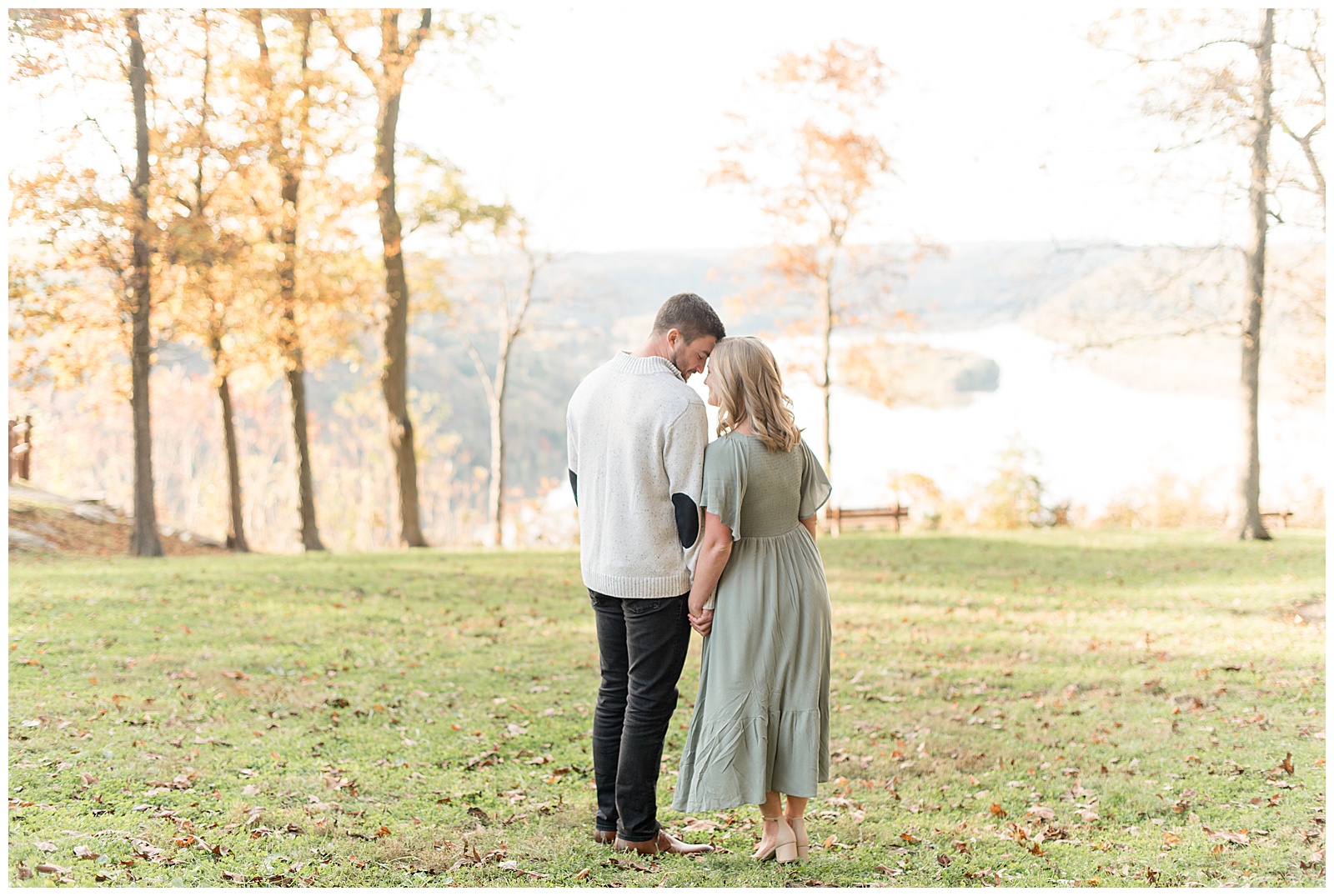 couple with their backs toward camera as they touch foreheads together on sunny fall day with the susquehanna river in the background