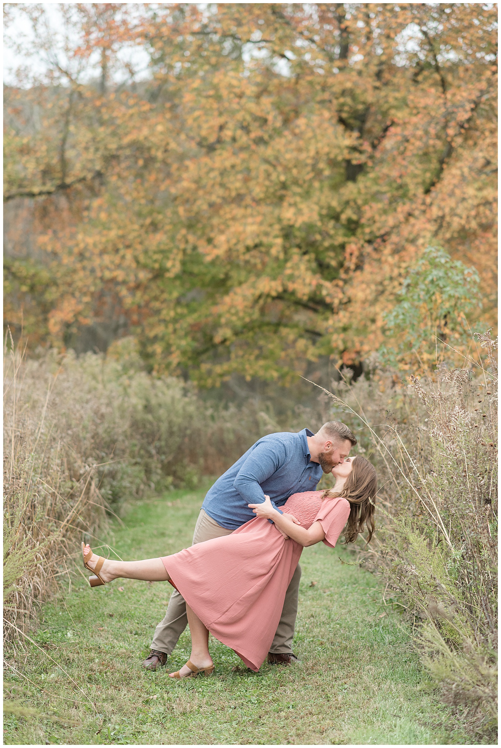 guy dipping girl backwards as they kiss with her left leg kicked up in aisle between tall wild grasses at middle creek wildlife preserve