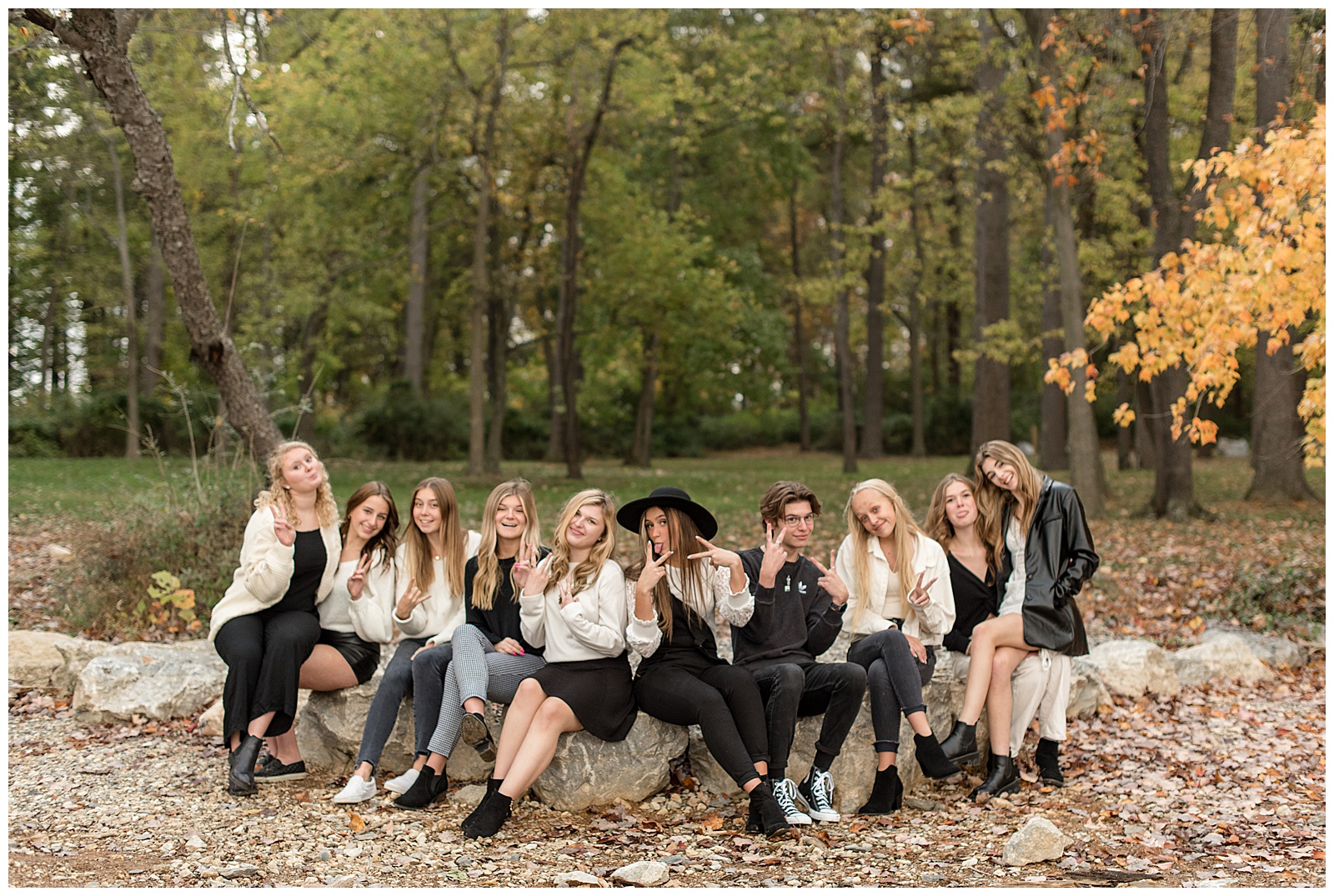 class of 2022 senior spokesmodels sitting side-by-side on low concrete wall at reservoir park with green trees behind them