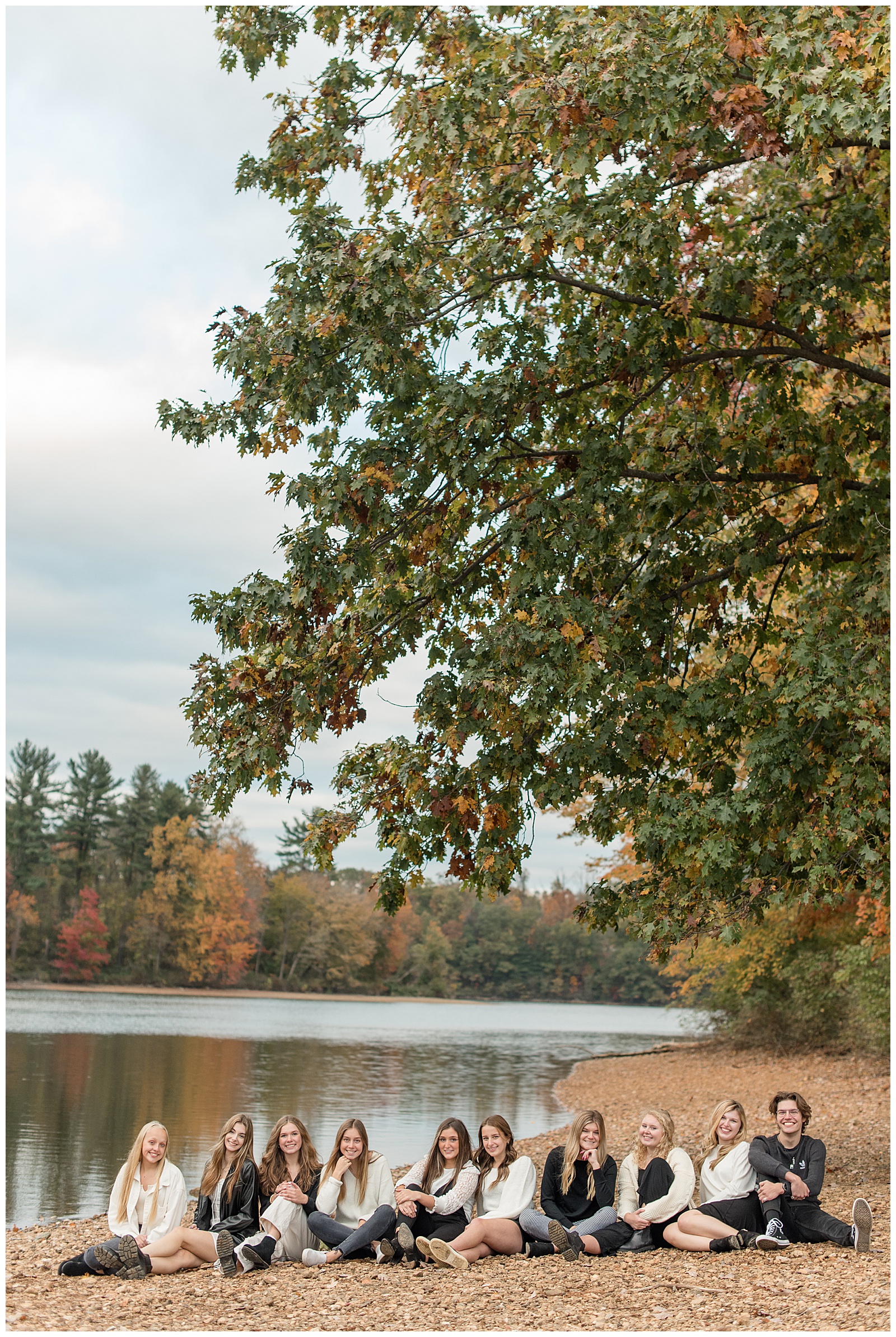 ten senior spokesmodels all sitting side-by-side on leaf-covered ground beside lake at reservoir park in york pennsylvania