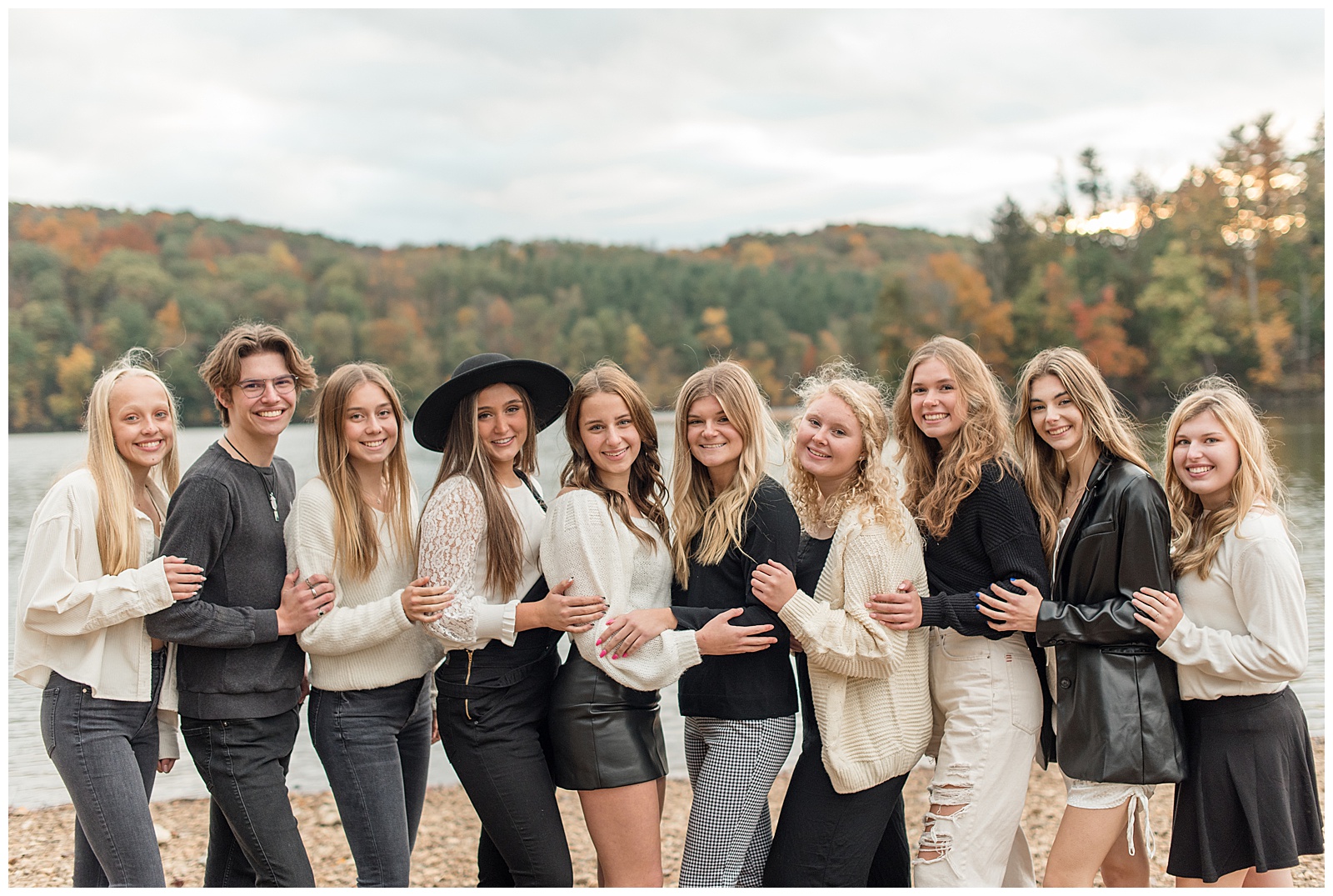 class of 2022 senior spokesmodels huddled close together resting hand on arm of person in front of them while smiling at camera by lake at reservoir park