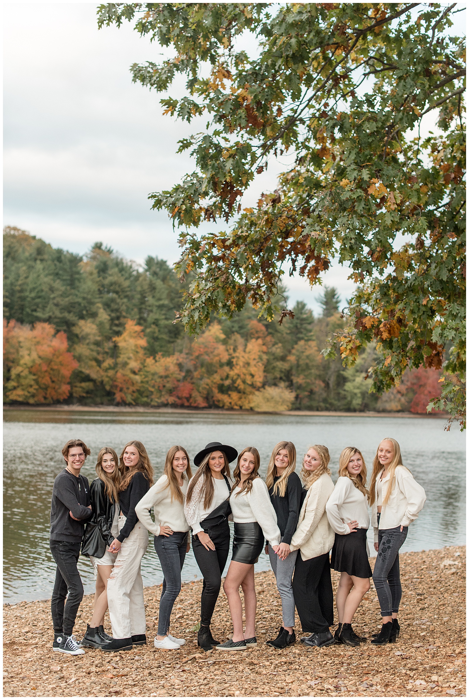 senior spokesmodel group all standing close with some facing right and others facing left by lake with colorful trees in york pennsylvania