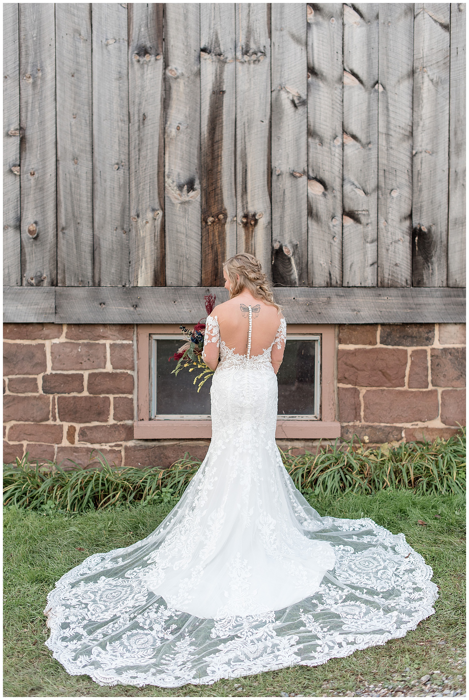 back of bride towards camera with her bridal gown train displayed by rustic barn in york pennsylvania