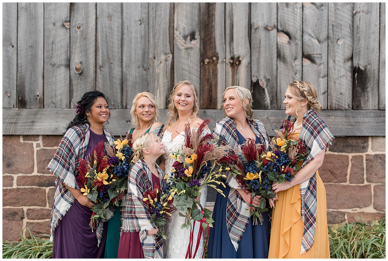 bride with her bridesmaids all smiling and looking at each other holding beautiful fall bouquets by barn at walnut grove farms