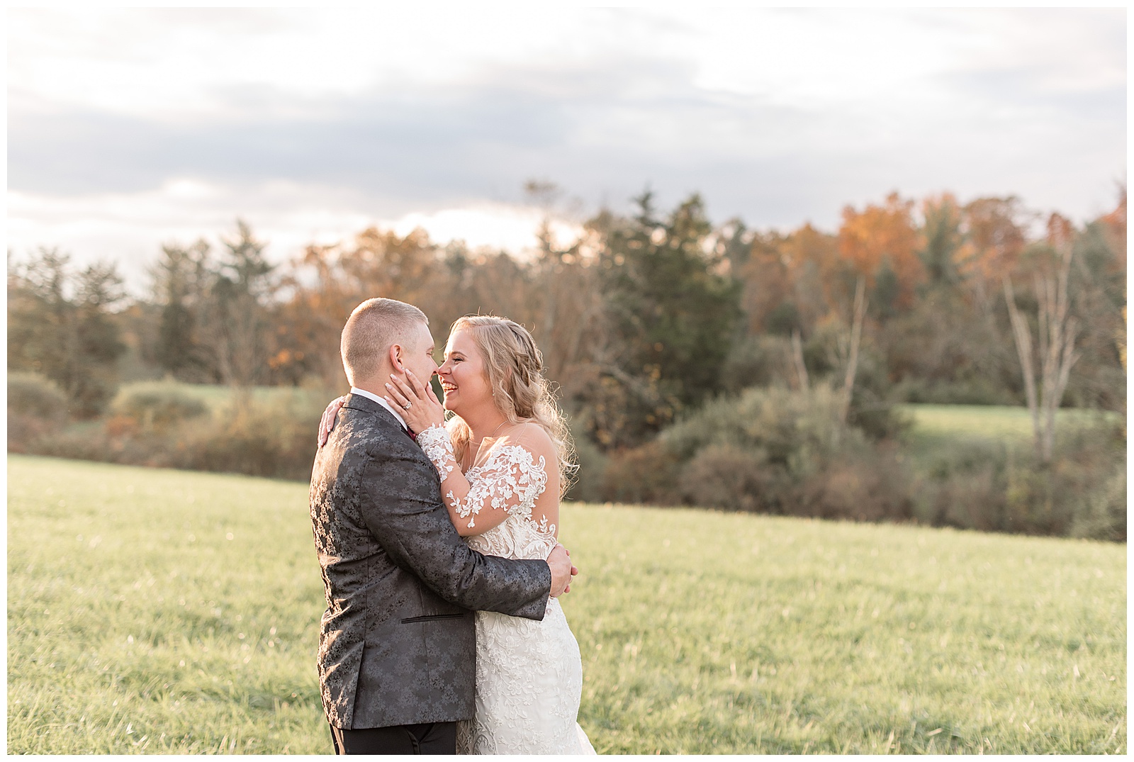 bride and groom kissing in grass field with colorful fall trees behind them at walnut grove farms