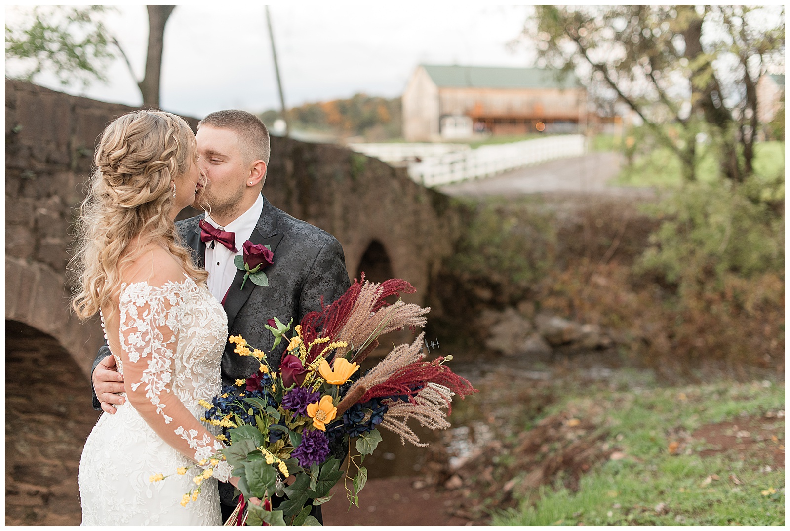 bride and groom kissing as bride holds beautiful fall bouquet near old bridge at walnut grove farms