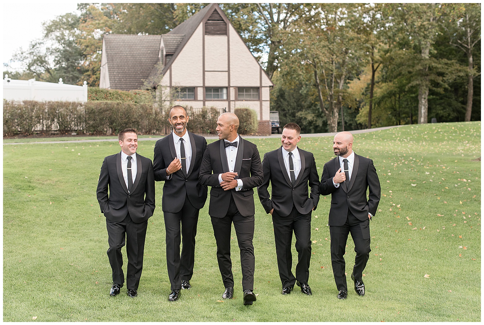 groom adjusting his cuff link as he and his groomsmen all walk towards camera on fairway at north jersey country club