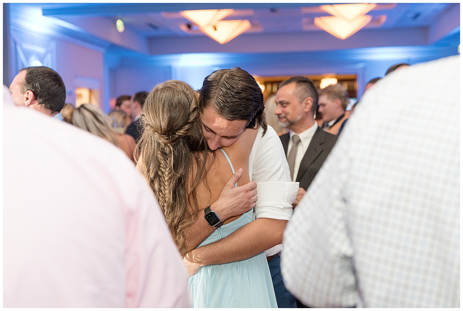 guests dancing during reception and guy hugging bridesmaid wearing light blue gown