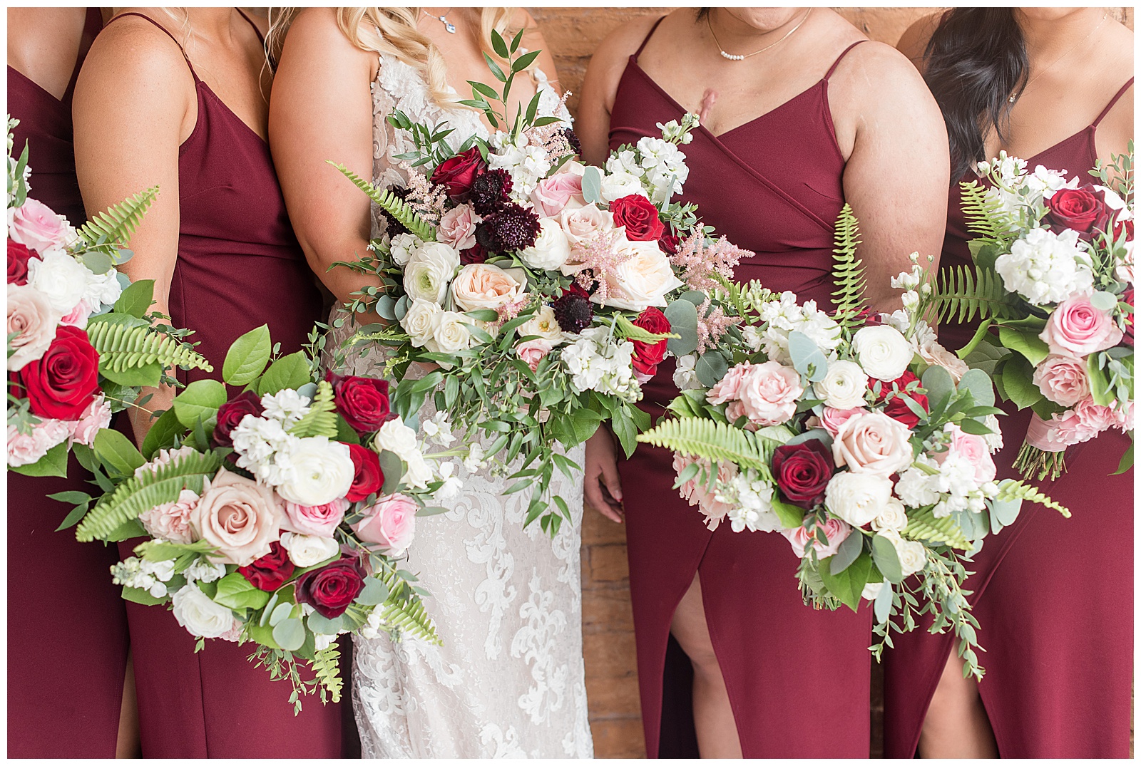 close up photo of bride and bridesmaid bouquets filled with red, maroon, light pink, and white roses