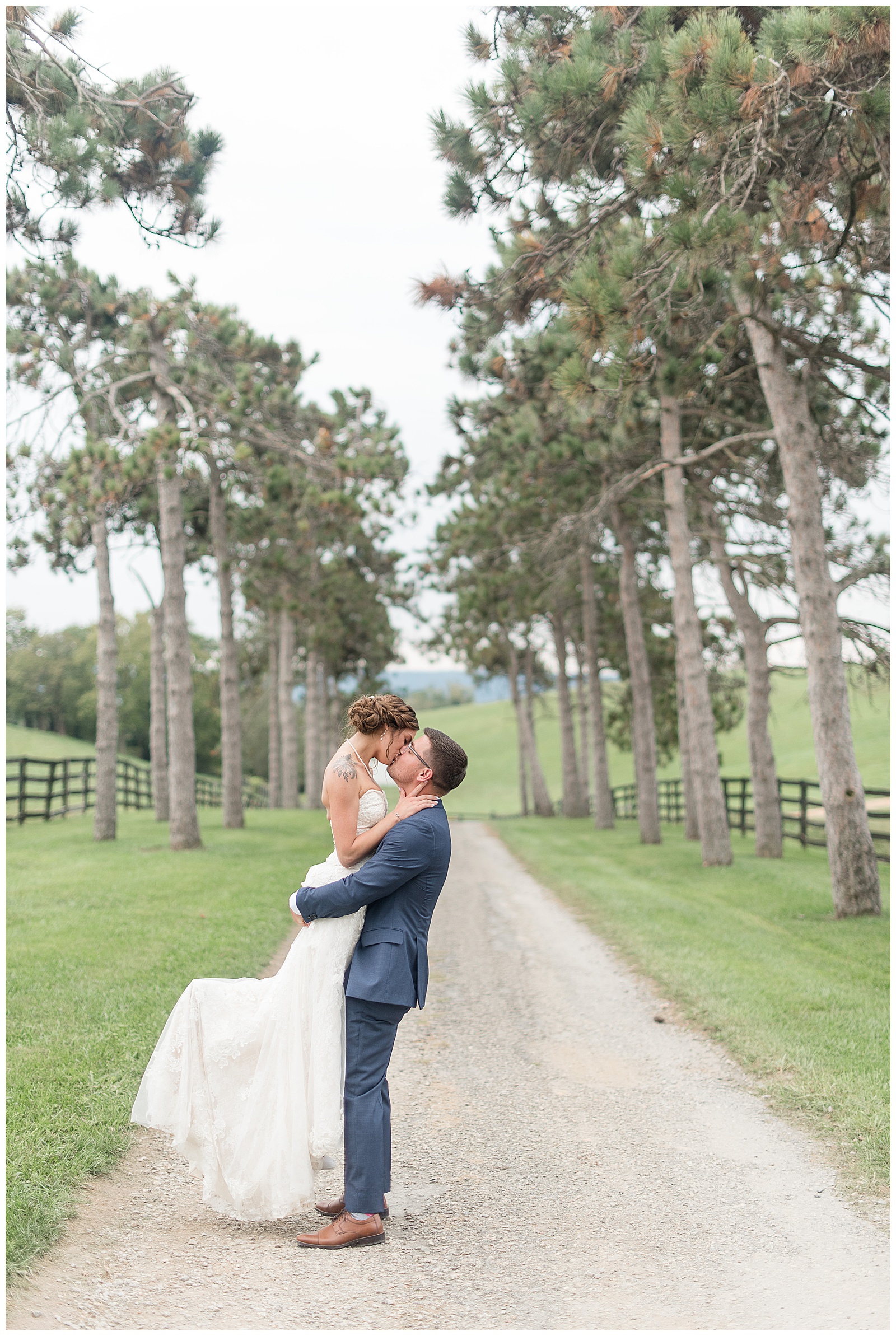 groom lifting his bride off they ground as they kiss along dirt road at lauxmont farms in york county pennsylvania