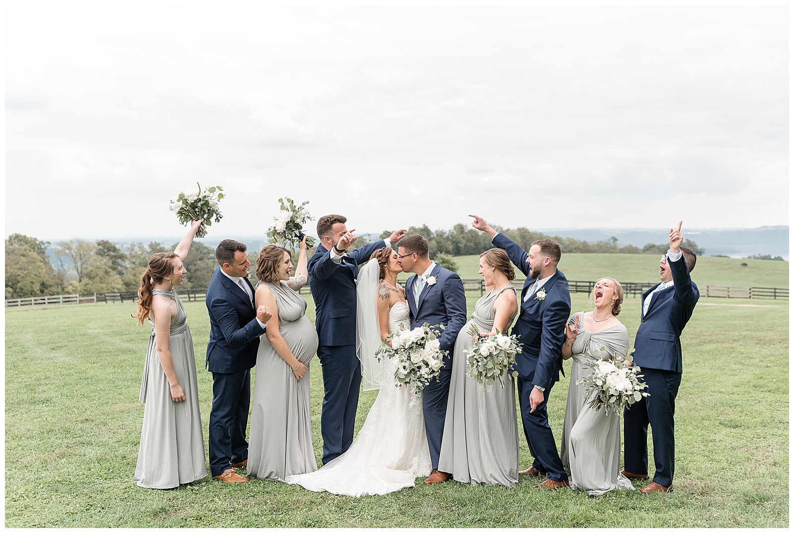 bride and groom kissing as their wedding party surrounds them cheering with arms extended in excitement at lauxmont farms