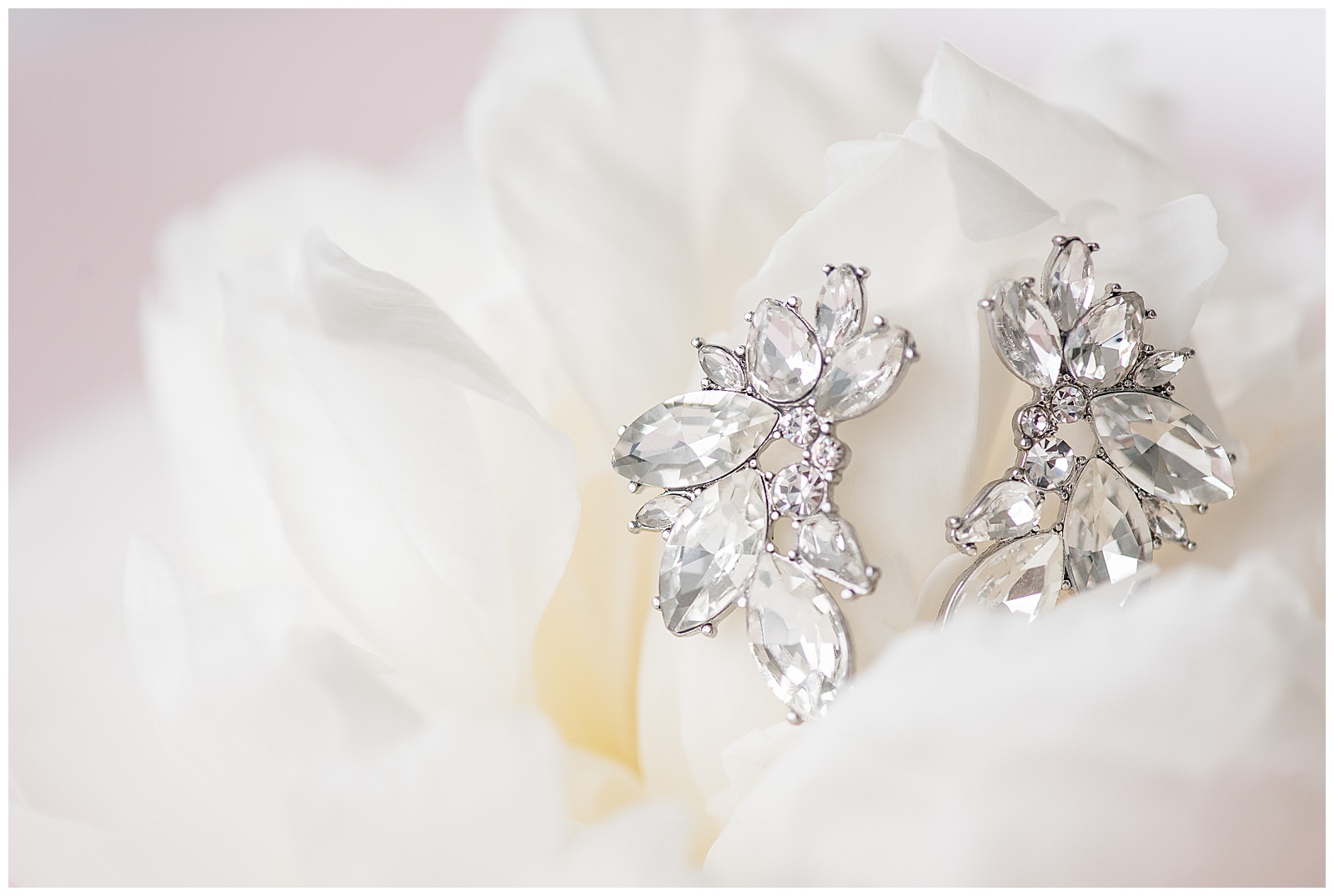 lovely diamond earrings nestled into white peony flower with light pink background